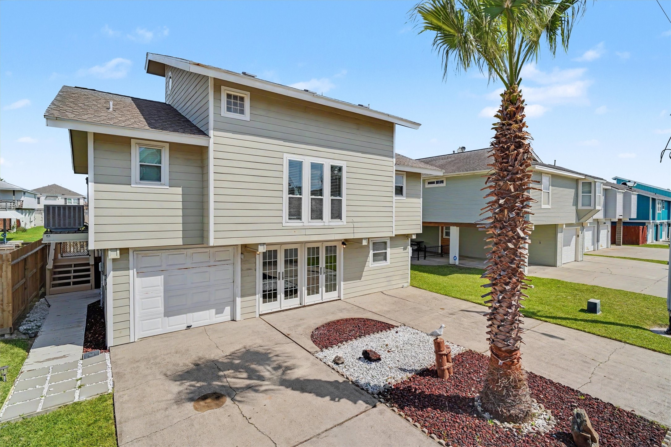 Street side view of home. The french doors enter into the downstairs flex room. The palm trees were recently trimmed
