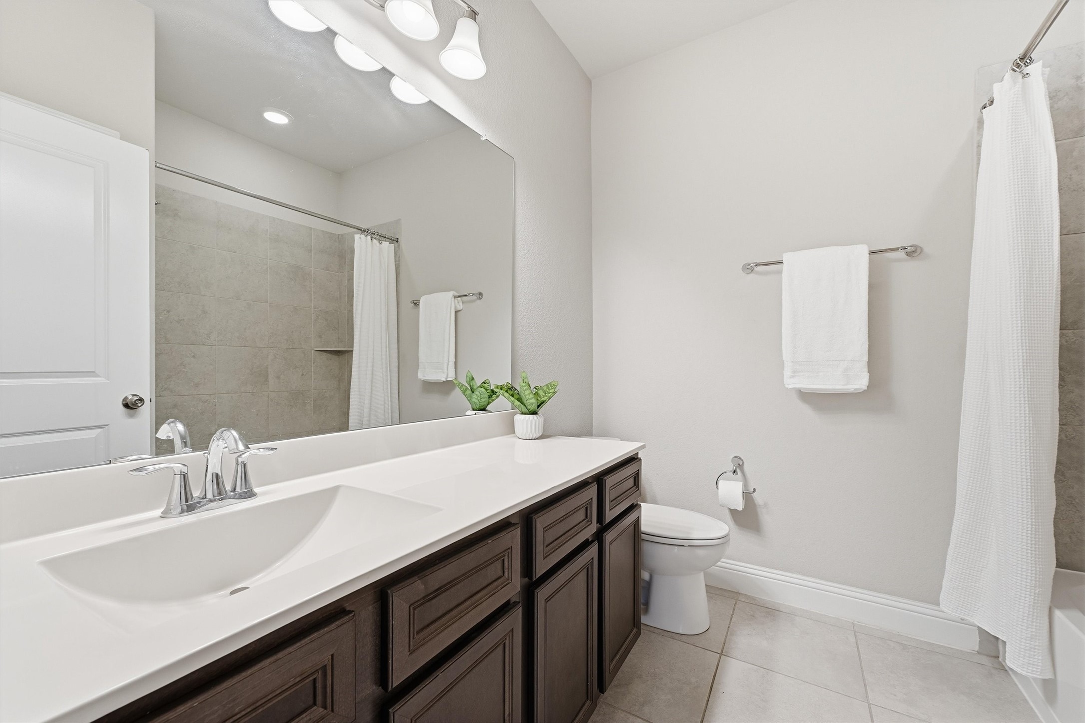 Secondary bath with generous counter space, ample vanity storage and a tiled tub/shower combination.