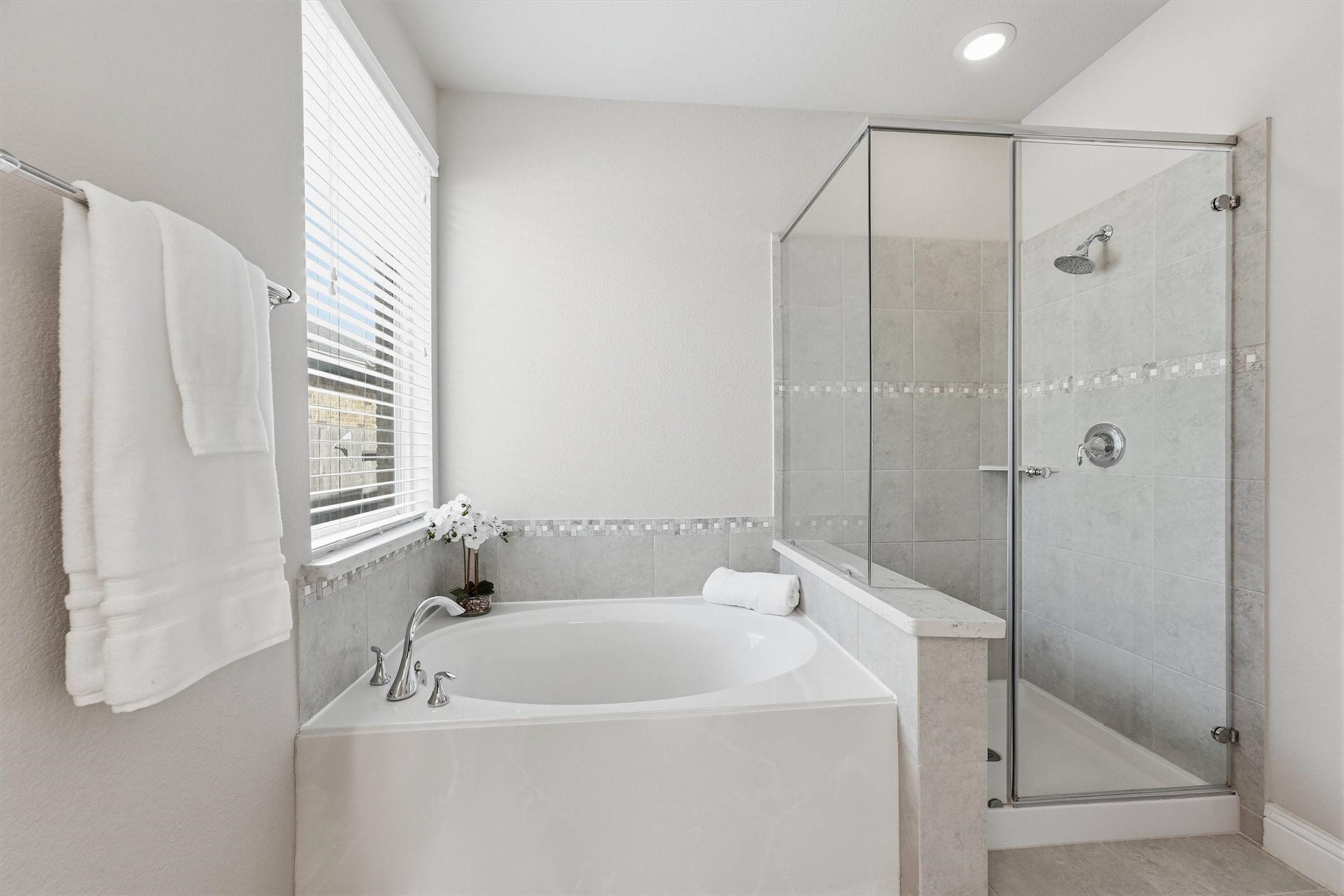 Primary bath with a soaking tub, separate glass-enclosed shower and decorative tile accents.