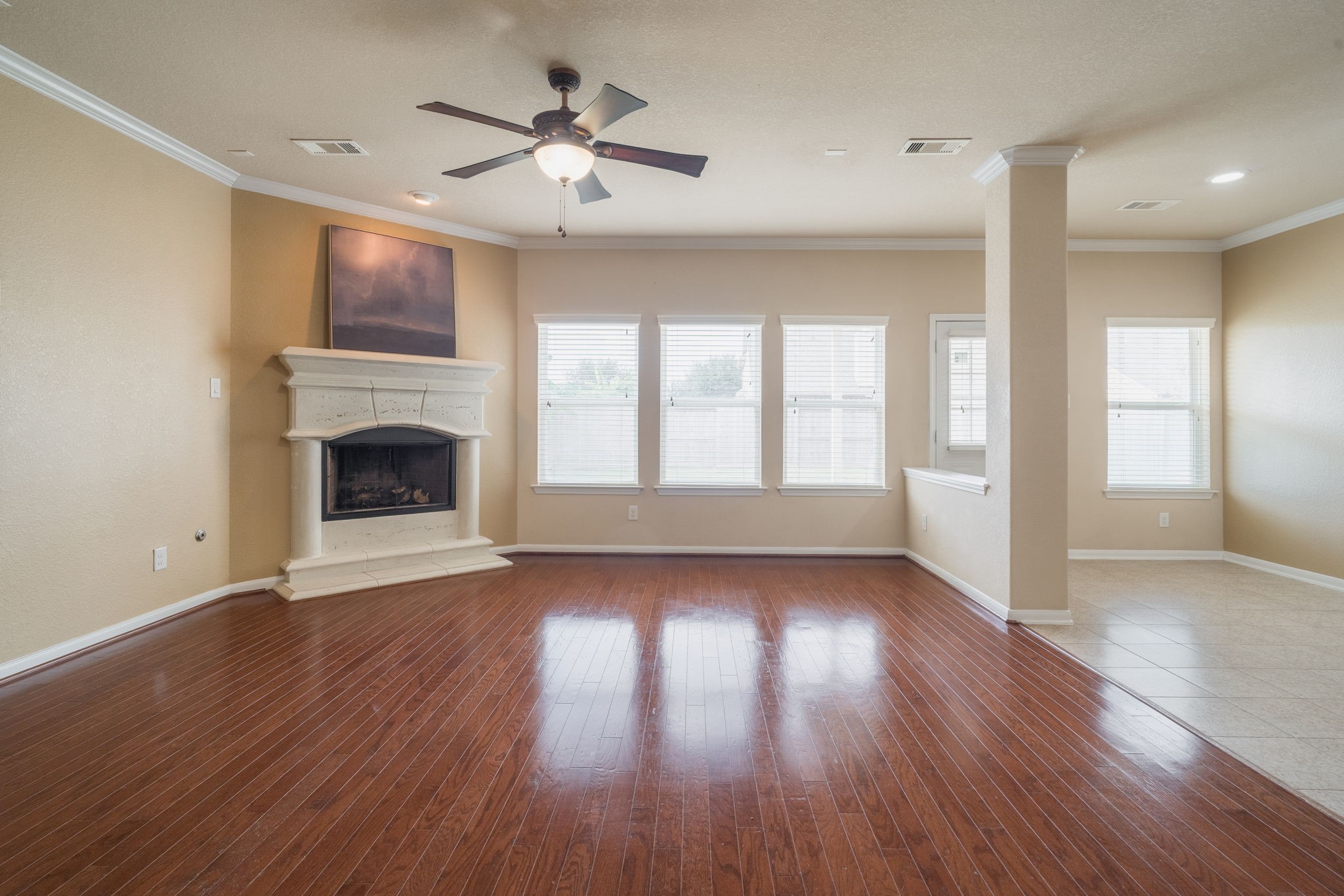Spacious family room featuring rich wood flooring, crown molding & a beautiful stone fireplace.