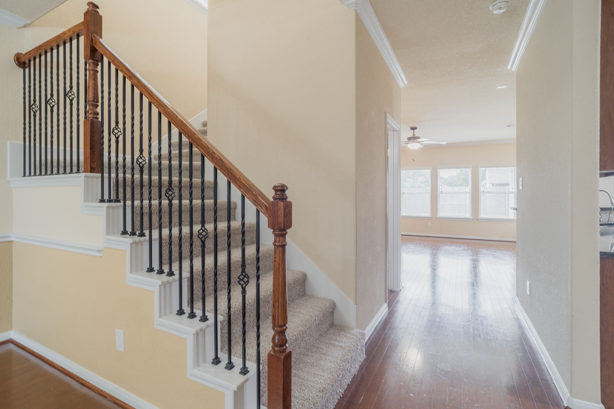 The entryway features rich wood flooring & a beautiful staircase with wrought iron balusters, wood handrails & carpeted steps, creating a welcoming transition to the second floor.