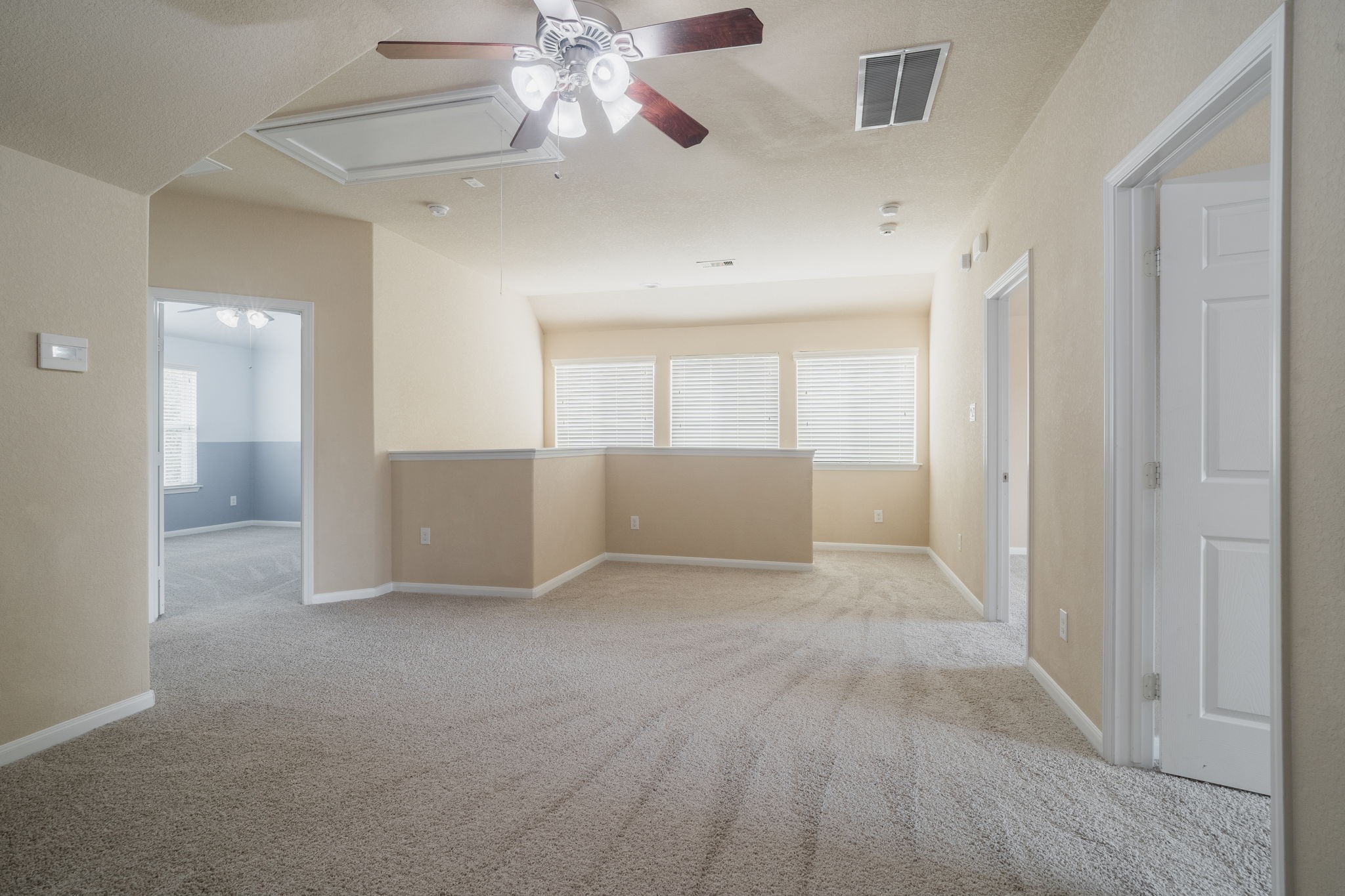 Another view of the upstairs game room showcasing its generous layout, abundant natural light & convenient access to the secondary bedrooms.