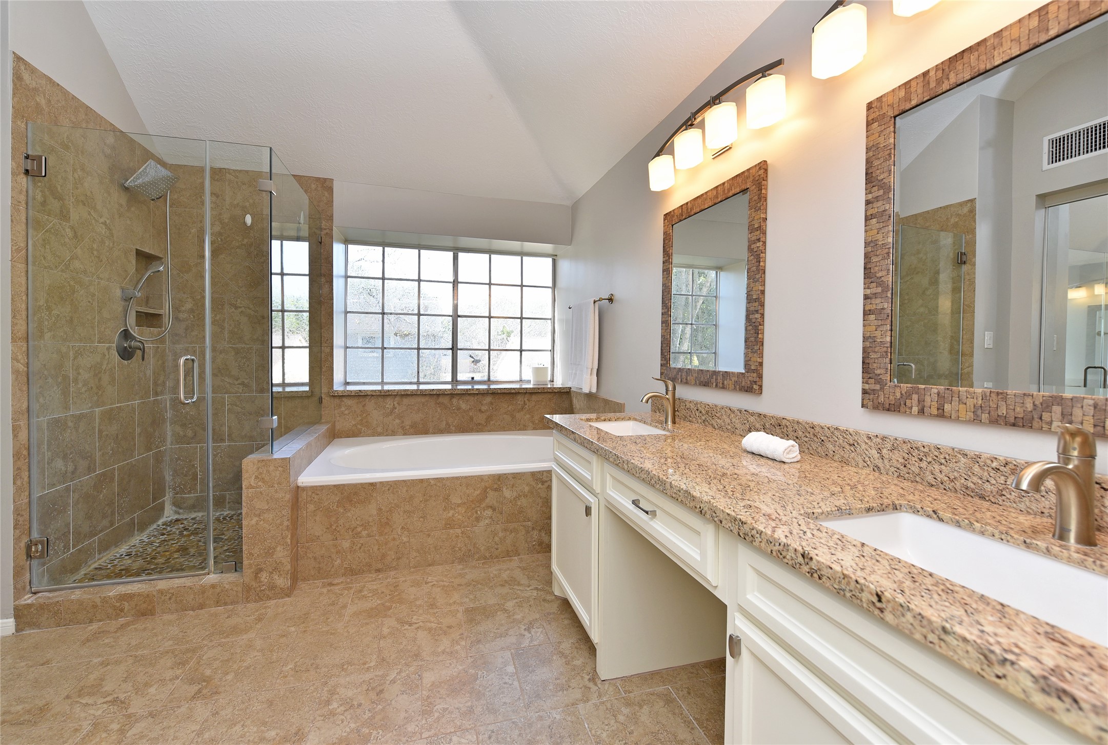 The remodeled primary bath features nice sized shower with pebble stone floor, a large garden tub and double sinks.