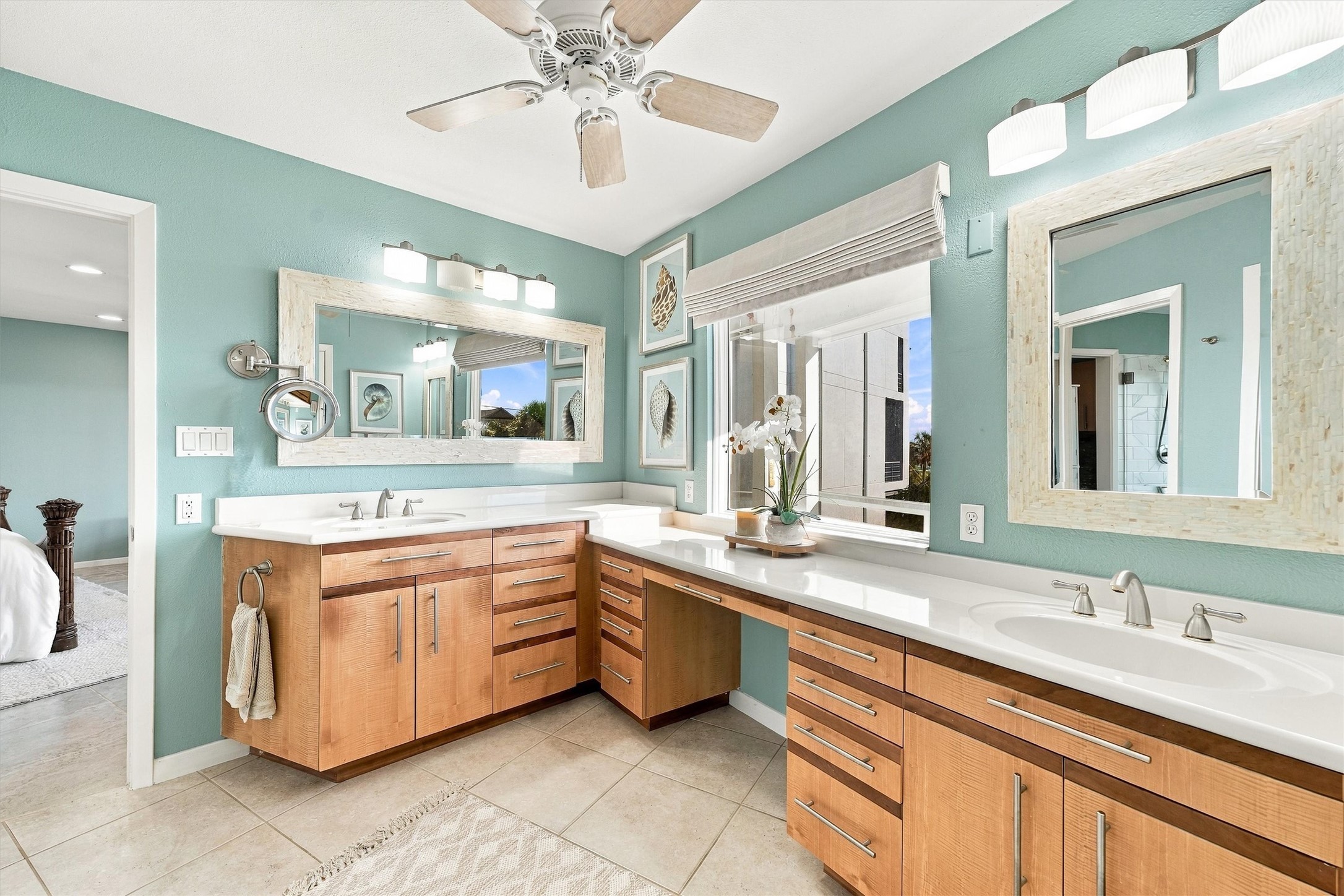 Sunlight spills across the spacious vanity as another island morning begins. Two sinks, a seated dressing area, and plentiful storage.