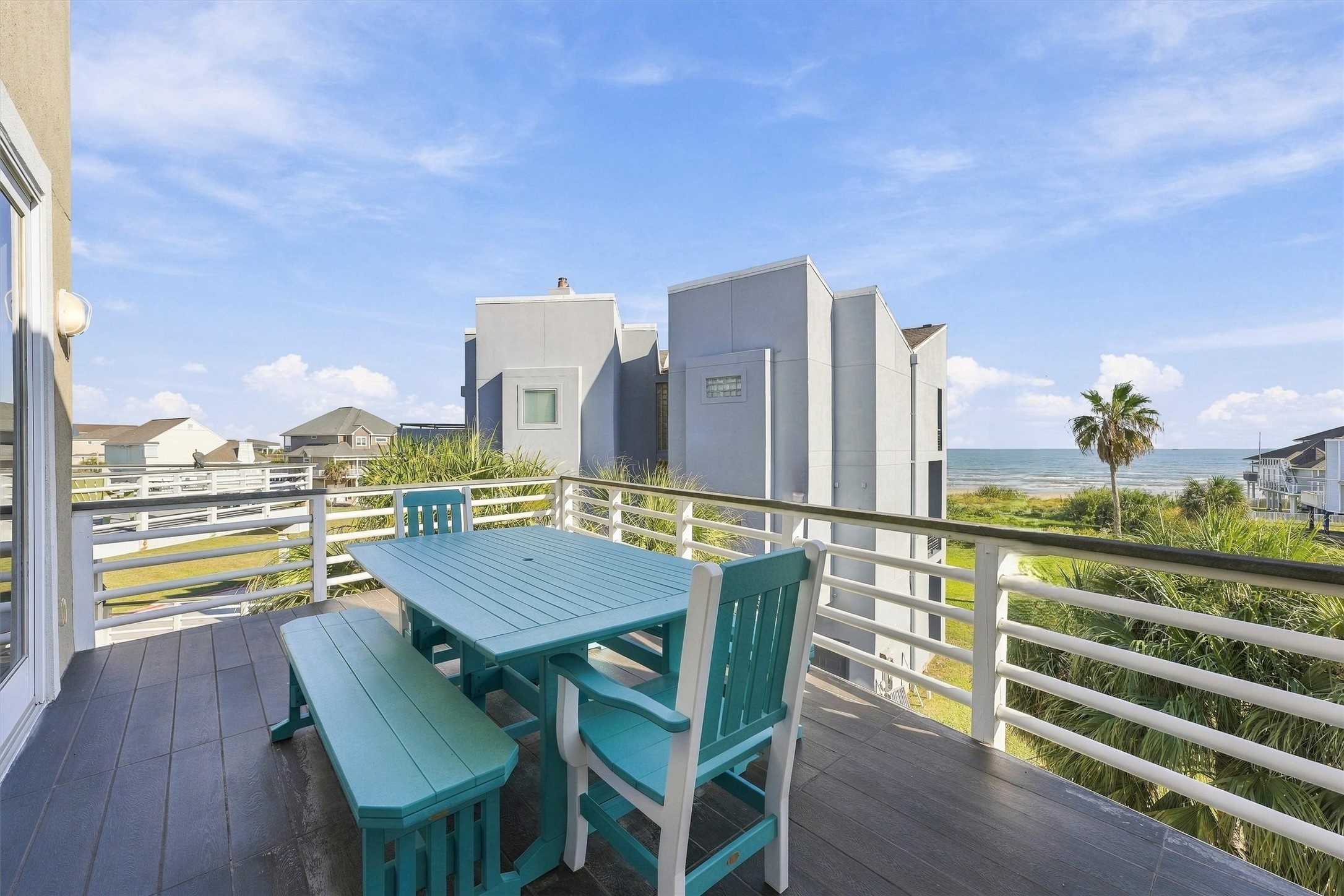 Start the morning with coffee and beach views, then gather for dinner in the coastal breeze. This spacious balcony offers an inviting setting for outdoor meals with palms and rolling waves beyond.