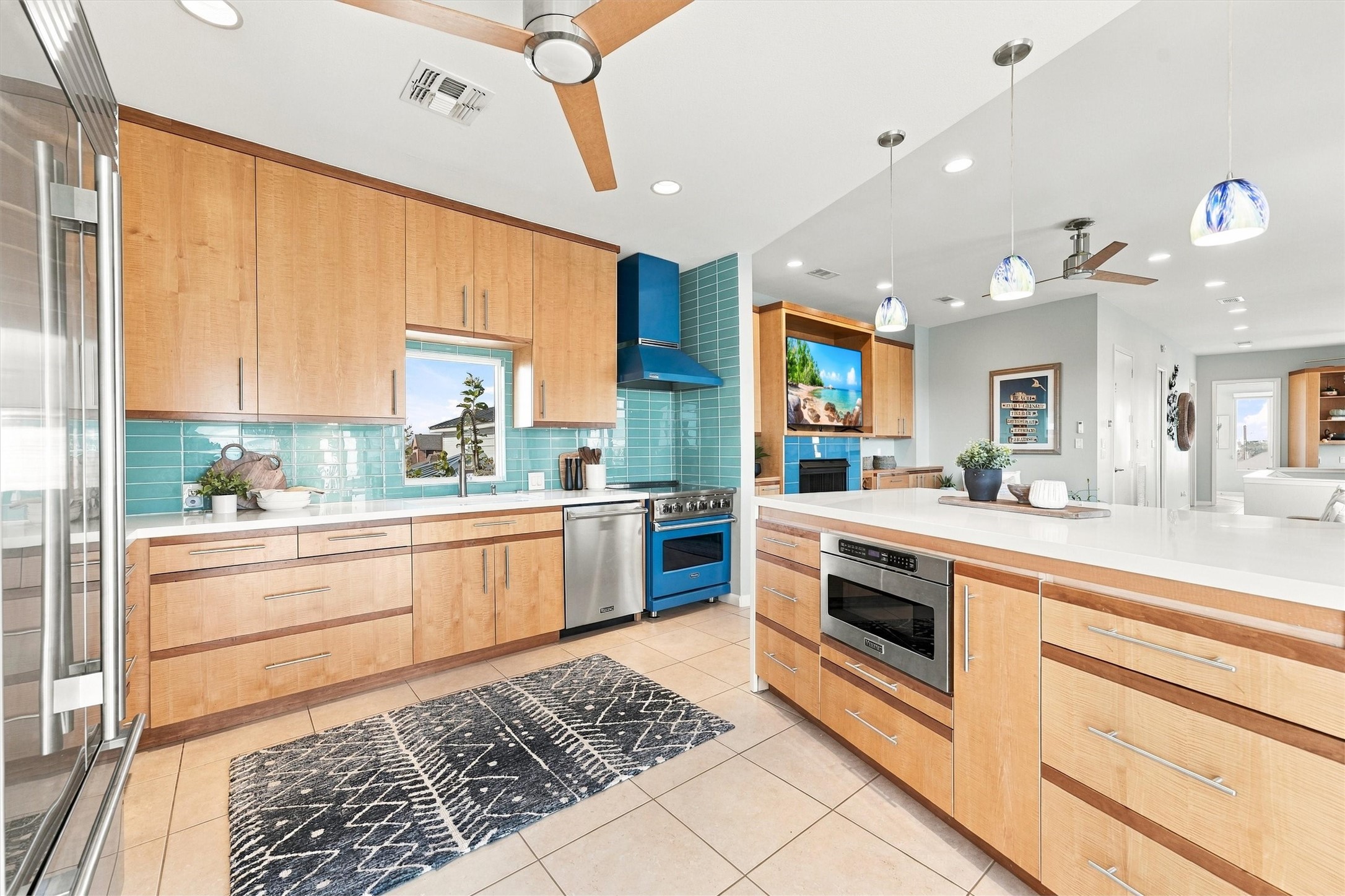 Gather around the generous kitchen counter. A striking blue range, sea-glass-colored backsplash, and warm wood cabinetry make preparing meals part of the coastal experience. Gather around the generous kitchen counter. A striking blue range, sea-glass-colored backsplash, and warm wood cabinetry make preparing meals part of the coastal experience.
