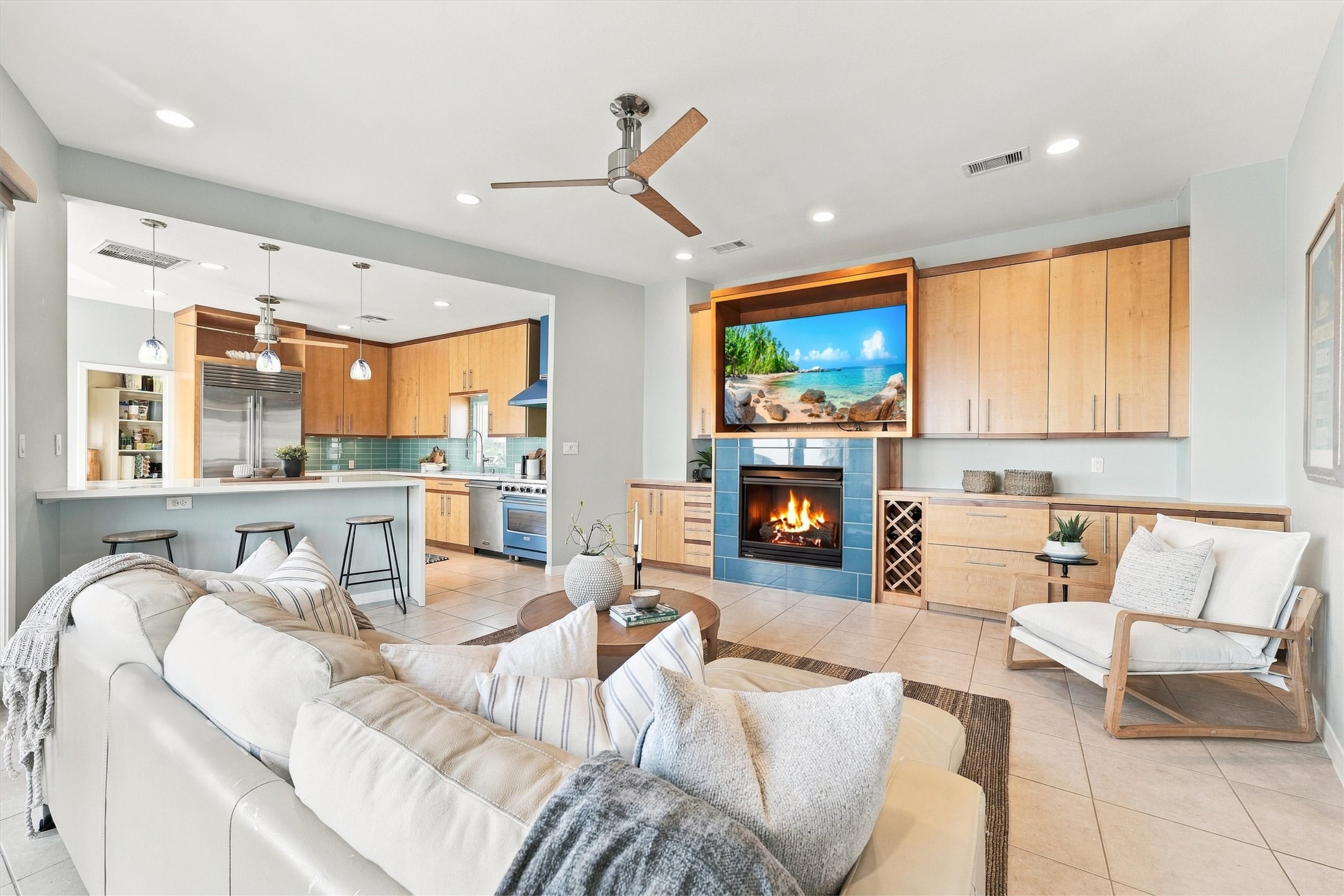 Keep the conversation flowing from the breakfast bar to the fireside seating area. The open layout brings everyone together, with warm wood built-ins, a wine rack, and coastal blue accents adding character.
