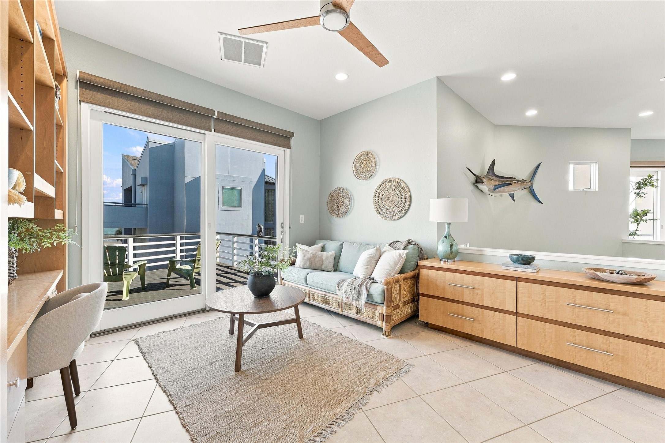 Natural textures and soft coastal colors create a welcoming spot for quiet conversation. Built-in drawers and shelving offer generous storage, and the adjoining balcony extends your living space into the island air.