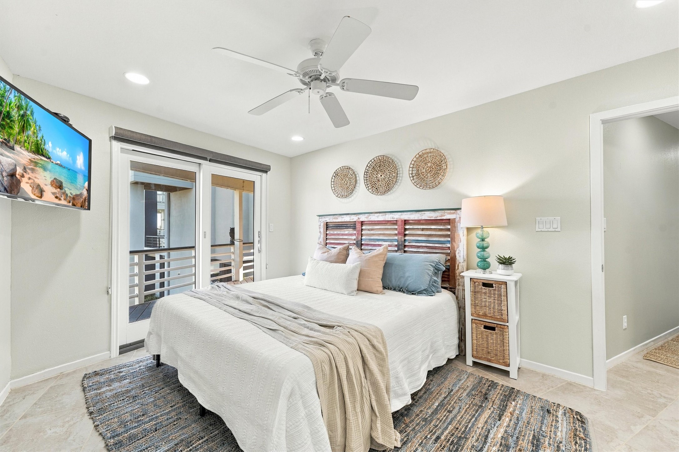 After a day along the shore, retreat to a restful bedroom filled with coastal charm. Soft blues, woven textures, and sliding glass doors to the covered balcony create a welcoming place to unwind.