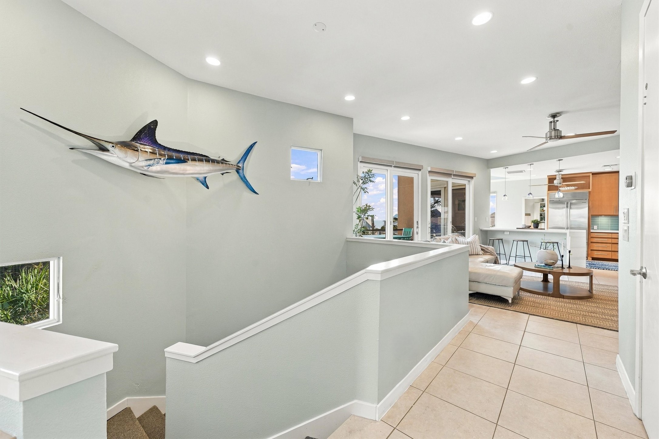 Head upstairs to the heart of the home, where the living area and kitchen come together in a bright, open layout. Coastal accents and two balconies set the scene for relaxed gatherings.