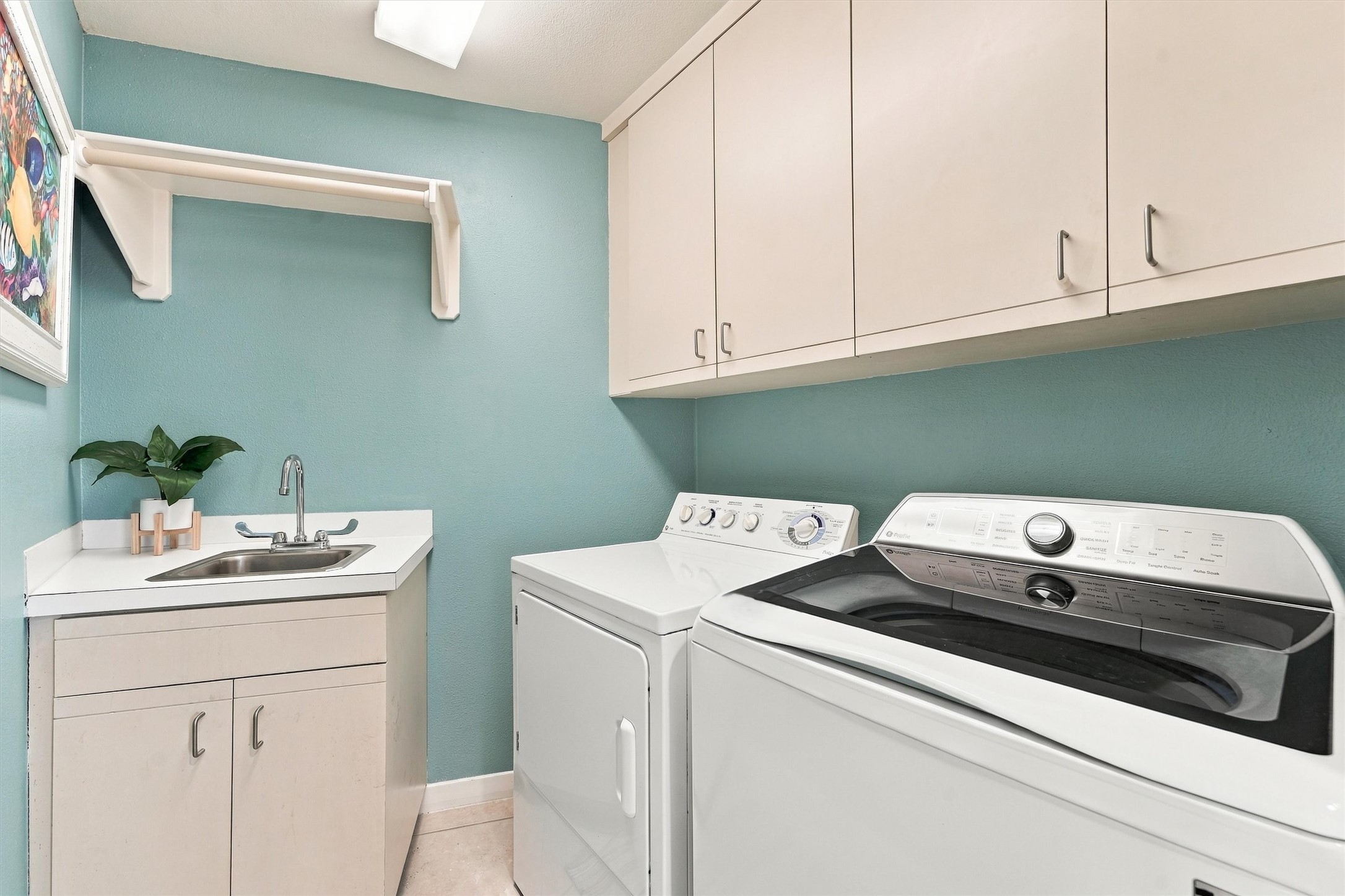 Keep beach towels fresh and swimsuits ready for another day by the water. This dedicated laundry room features a washer and dryer, utility sink, overhead cabinetry, and a hanging rod for everyday convenience.