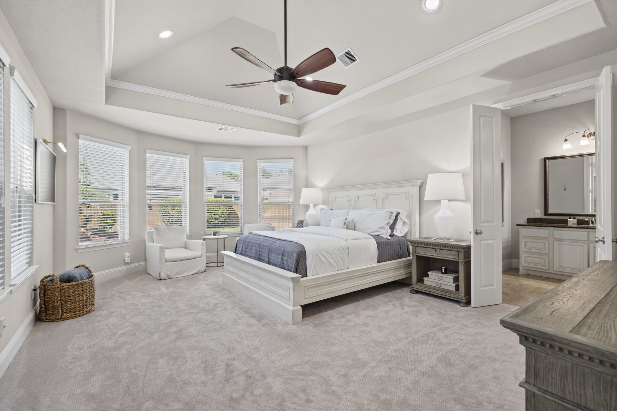 The spacious primary retreat offers an elegant tray ceiling, abundant natural light, and a relaxing sitting area, creating a peaceful and luxurious escape.