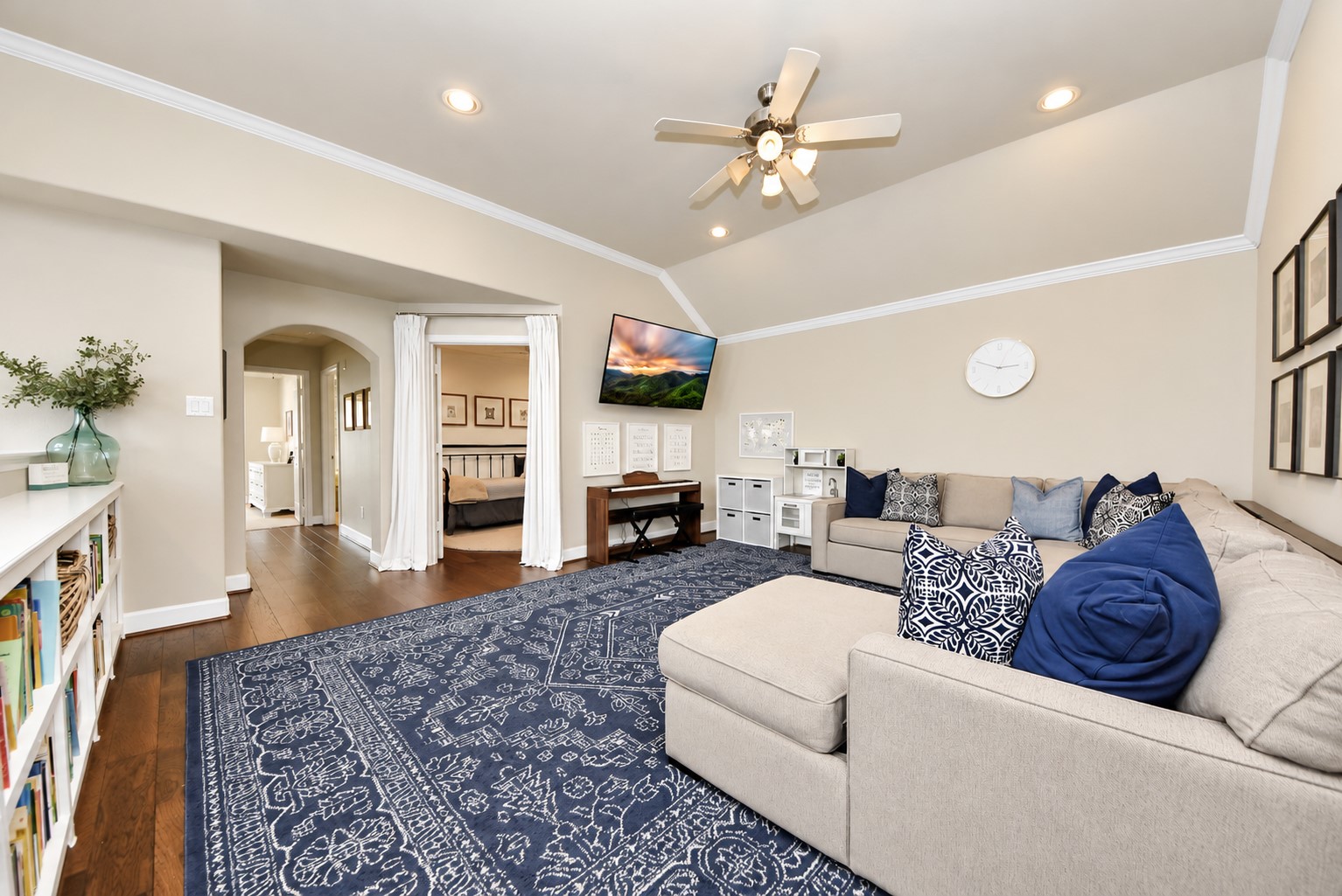Impressive upstairs game room featuring vaulted ceilings, beautiful hardwood flooring, custom built-in bookshelves, and plenty of space for entertaining and relaxing.