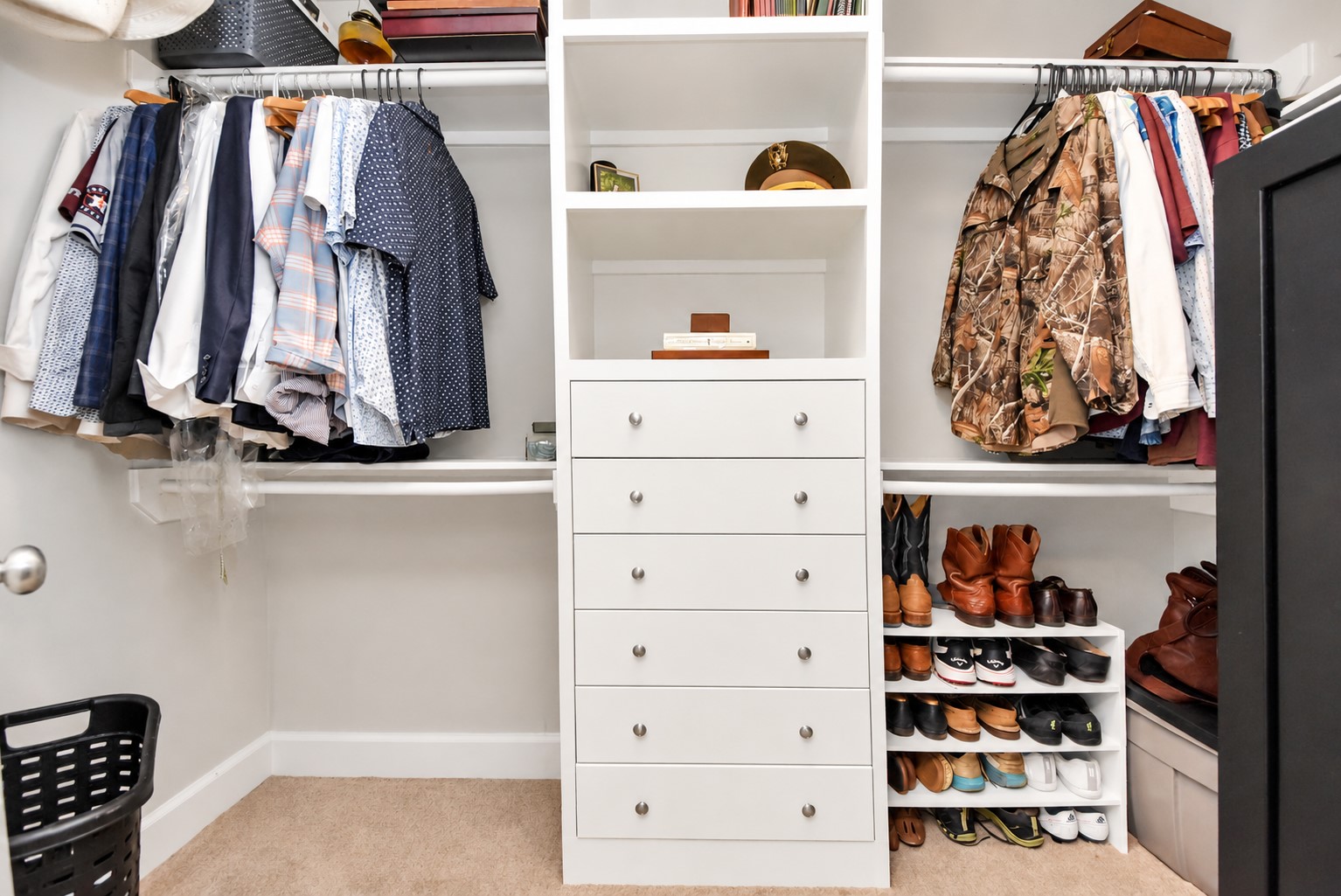 Spacious primary walk-in closet featuring custom built-in drawers, open shelving, and hanging storage.
