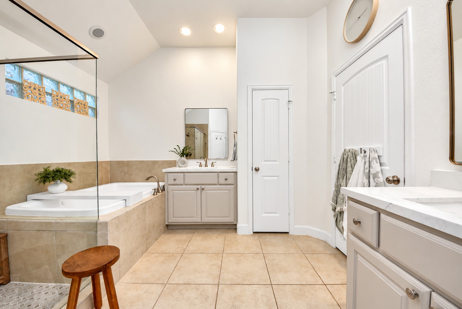 Spacious primary bathroom offering a soaking tub, separate vanities, and a bright, functional layout.