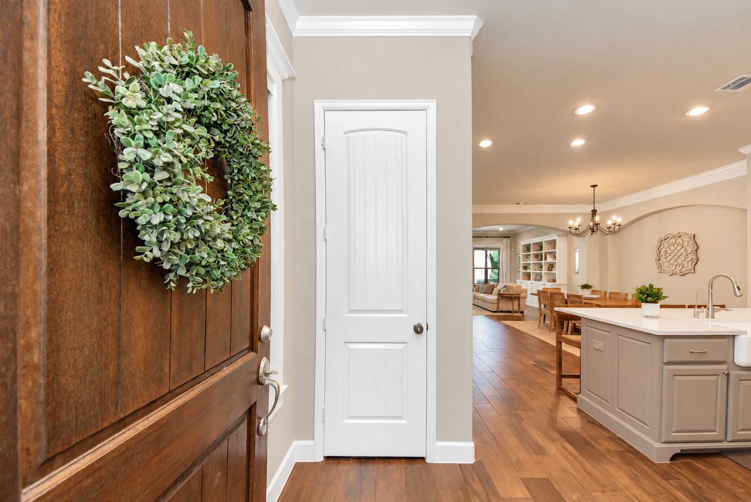 Welcoming entryway with rich wood flooring and an open view of the kitchen, dining, and living areas.