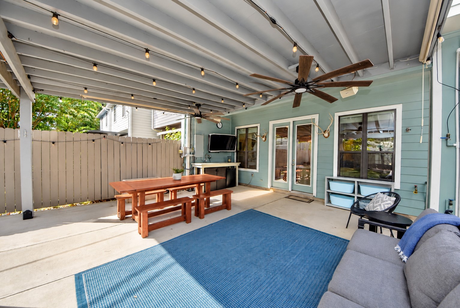 Fantastic covered patio featuring ceiling fans, string lighting, and generous space for outdoor dining, entertaining, or relaxing year-round.