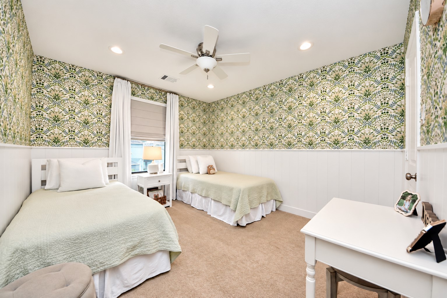 Beautifully designed secondary bedroom featuring custom wallpaper, classic white wainscoting, recessed lighting, and a spacious layout with room for multiple beds.