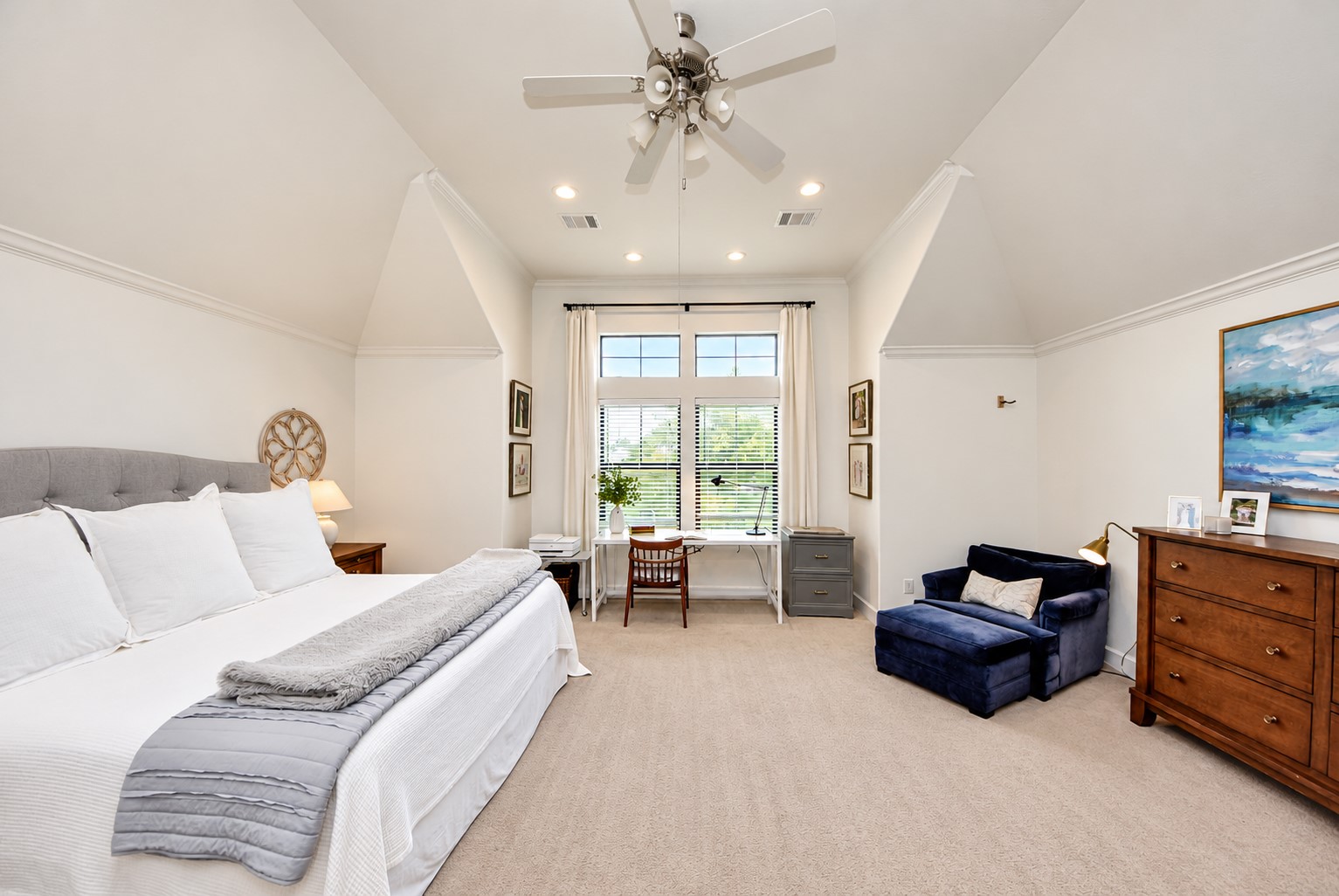 Generously sized primary bedroom featuring high ceilings, abundant natural light, and a comfortable sitting or workspace.
