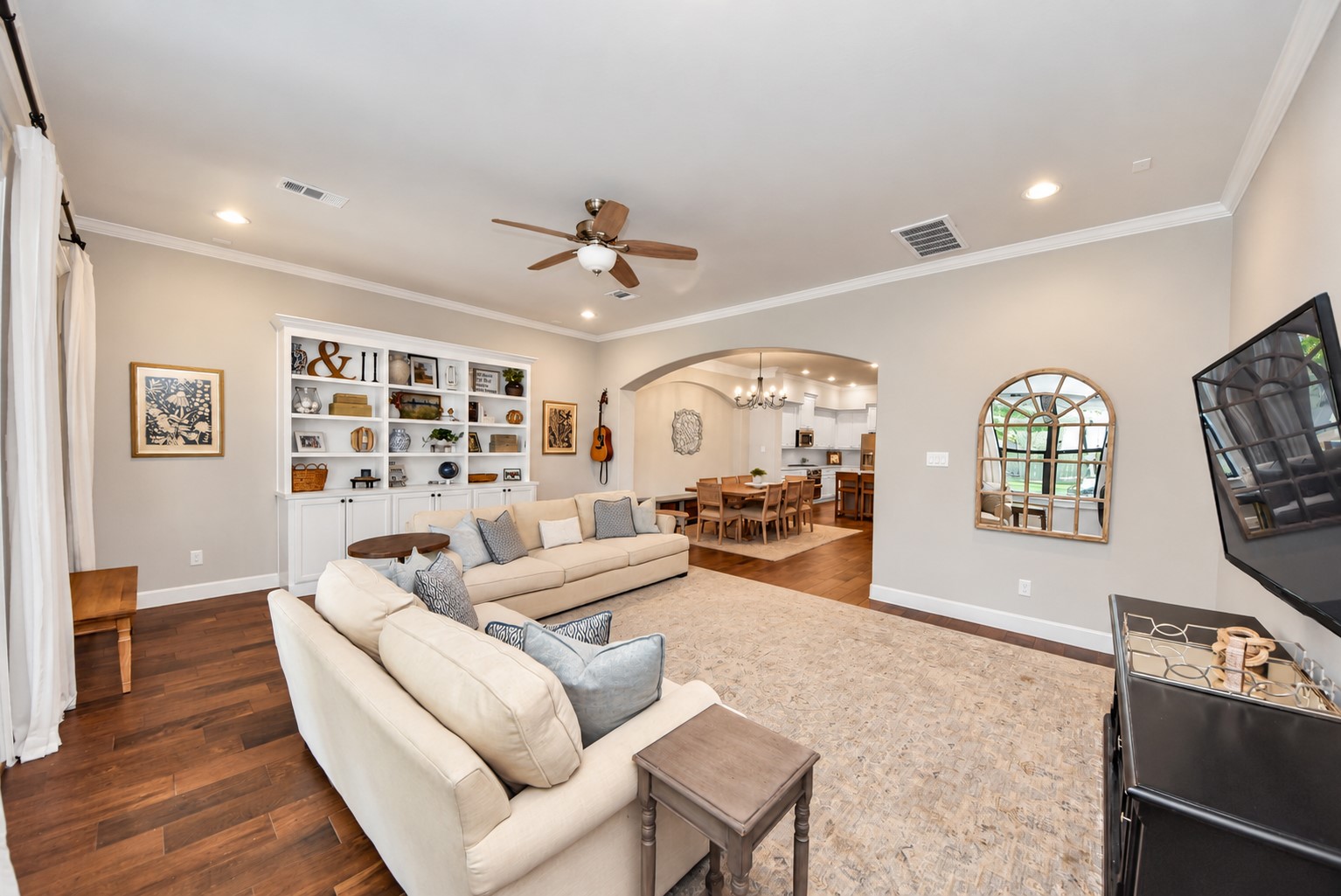 Another view of the living room highlighting the open floor plan, custom built-ins, and easy flow into the dining area.