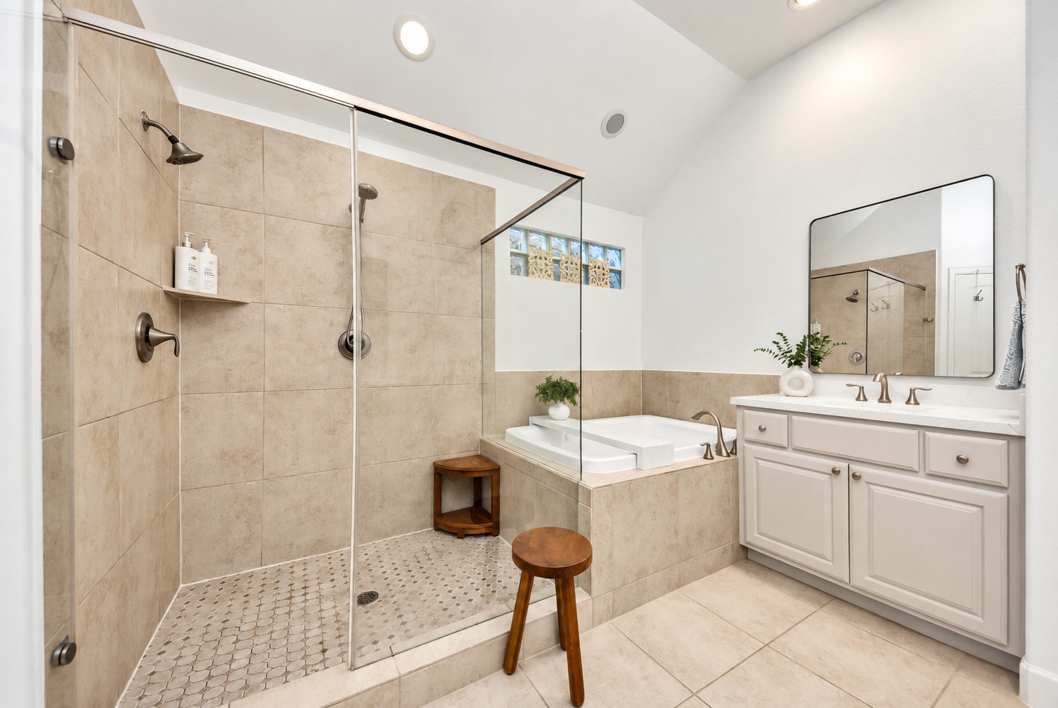 Beautiful primary bathroom featuring a glass-enclosed shower, soaking tub, and generous vanity storage.