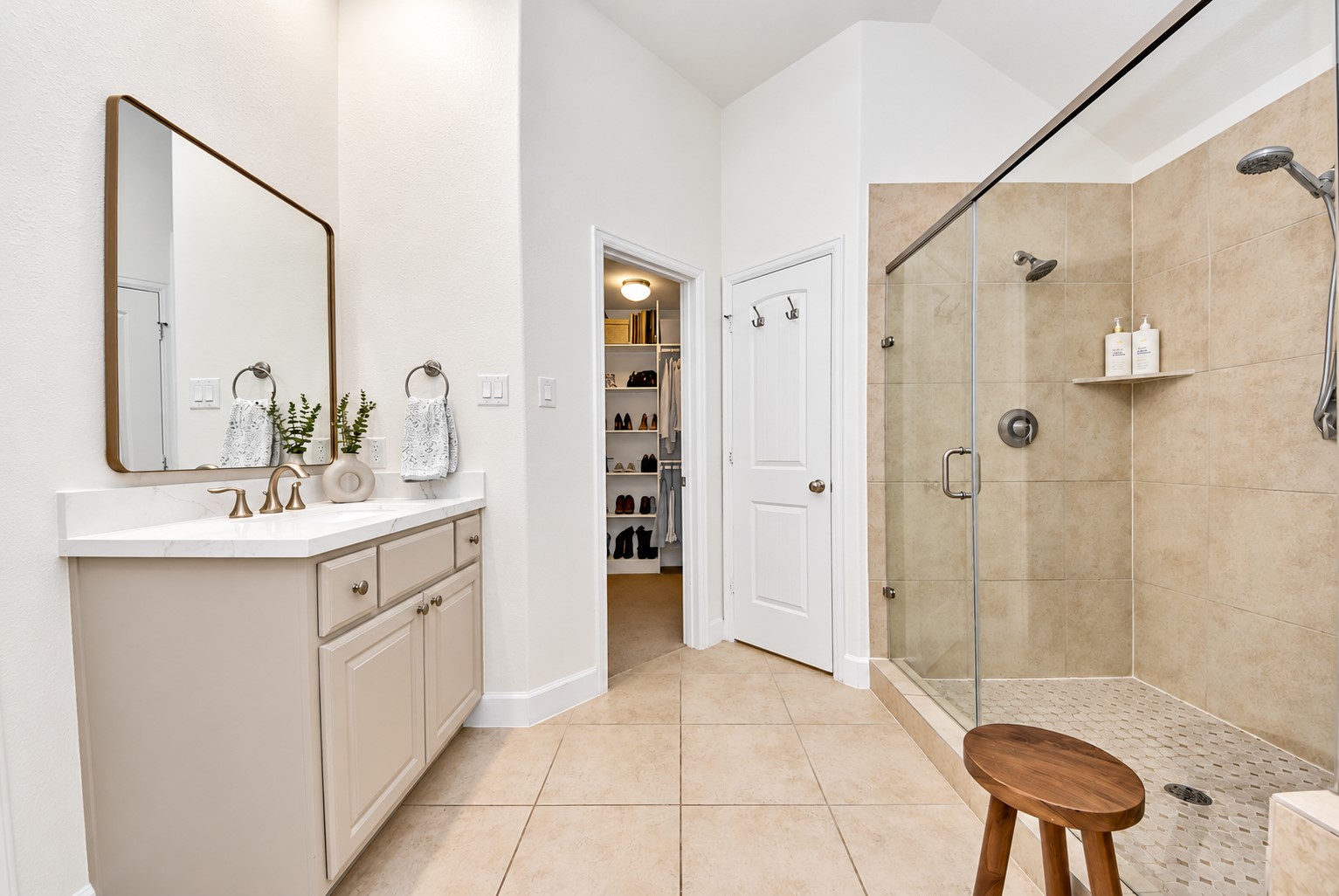 Primary bathroom with a spacious walk-in shower, neutral tile finishes, and direct access to the walk-in closet.