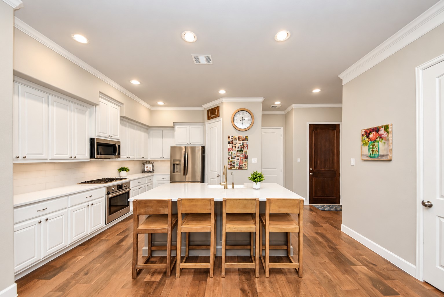 Spacious kitchen featuring white cabinetry, stainless steel appliances, generous counter space, and an oversized island with seating for four. Spacious kitchen featuring white cabinetry, stainless steel appliances, generous counter space, and an oversized island with seating for four.