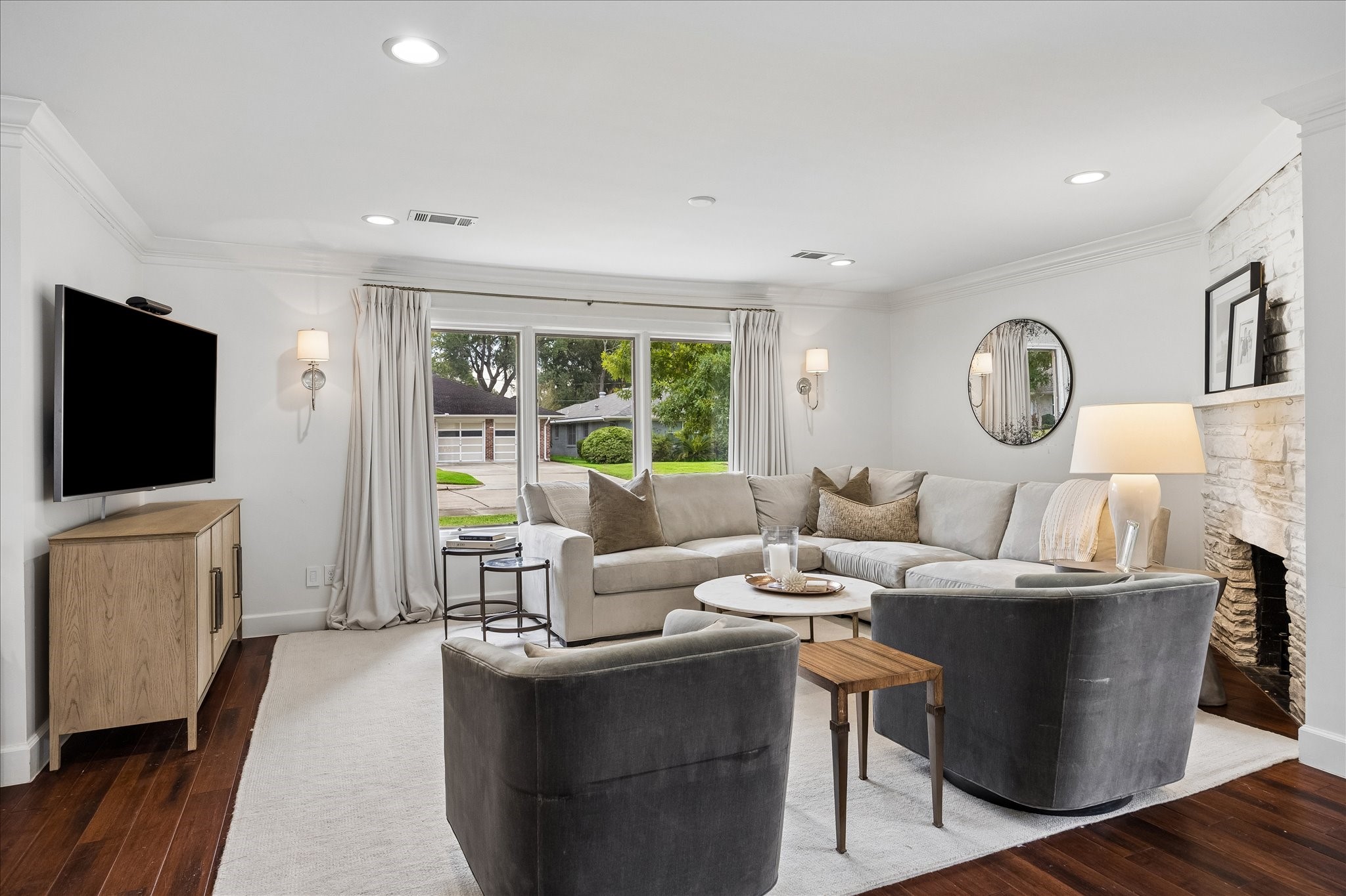 The living room boasts bamboo flooring, a mock fireplace, Visual comfort sconces and drapery. The living room boasts bamboo flooring, a mock fireplace, Visual comfort sconces and drapery.