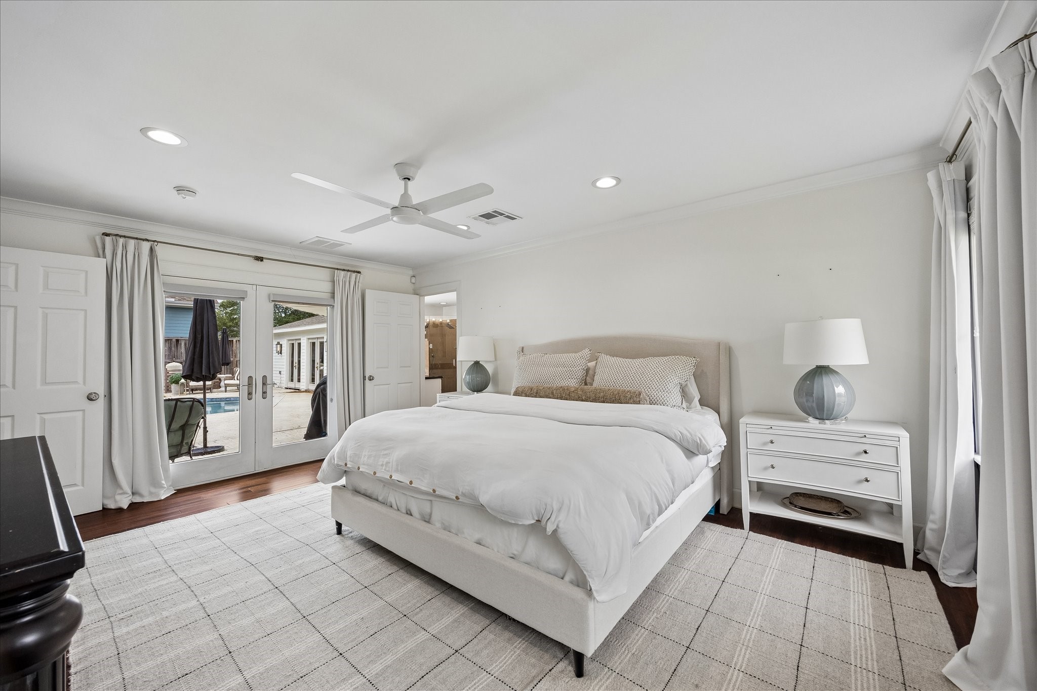 Primary bedroom with French doors leading to the pool and outdoor oasis.