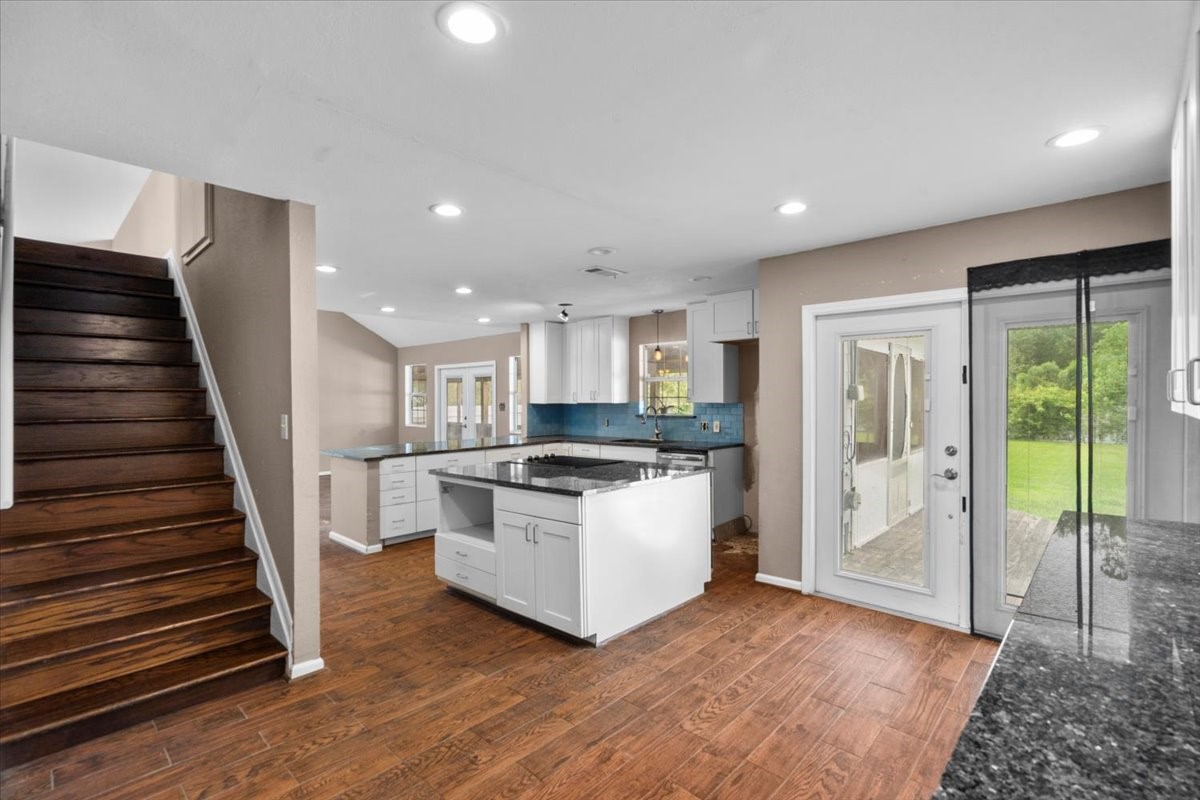 Expansive kitchen with second set of french doors onto back porch and stairs leading up to game room.