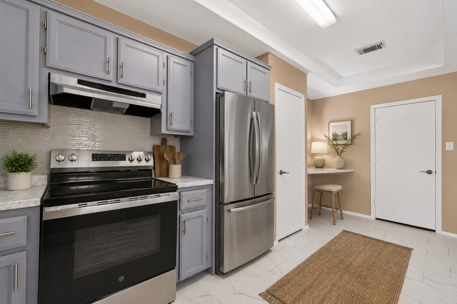 Nicely updated kitchen featuring painted cabinetry, marble countertops, stainless range an updated backsplash, and abundant cabinet space.