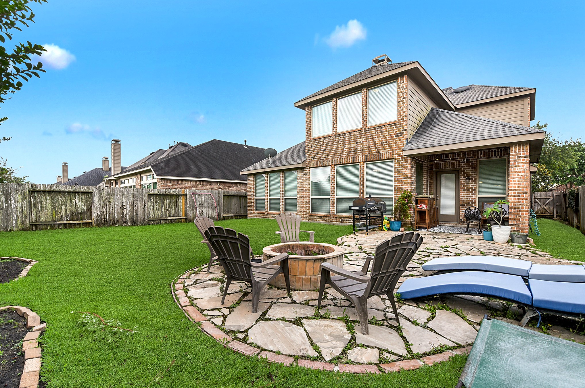 Another perspective of the spacious backyard reveals the covered patio and a separate seating area for the firepit, creating a welcoming outdoor retreat. Don't miss the opportunity to view this beautiful property! Schedule an appointment today.