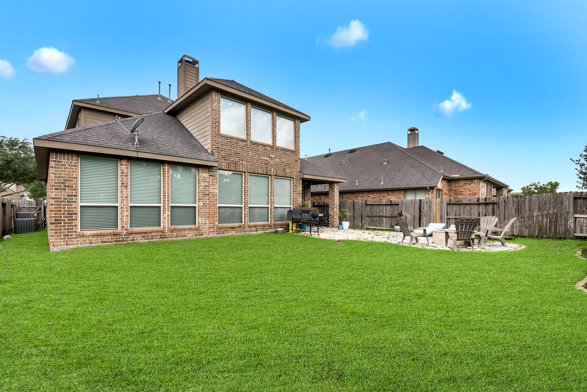 The larger backyard has a covered patio along with a separate seat area for a firepit.