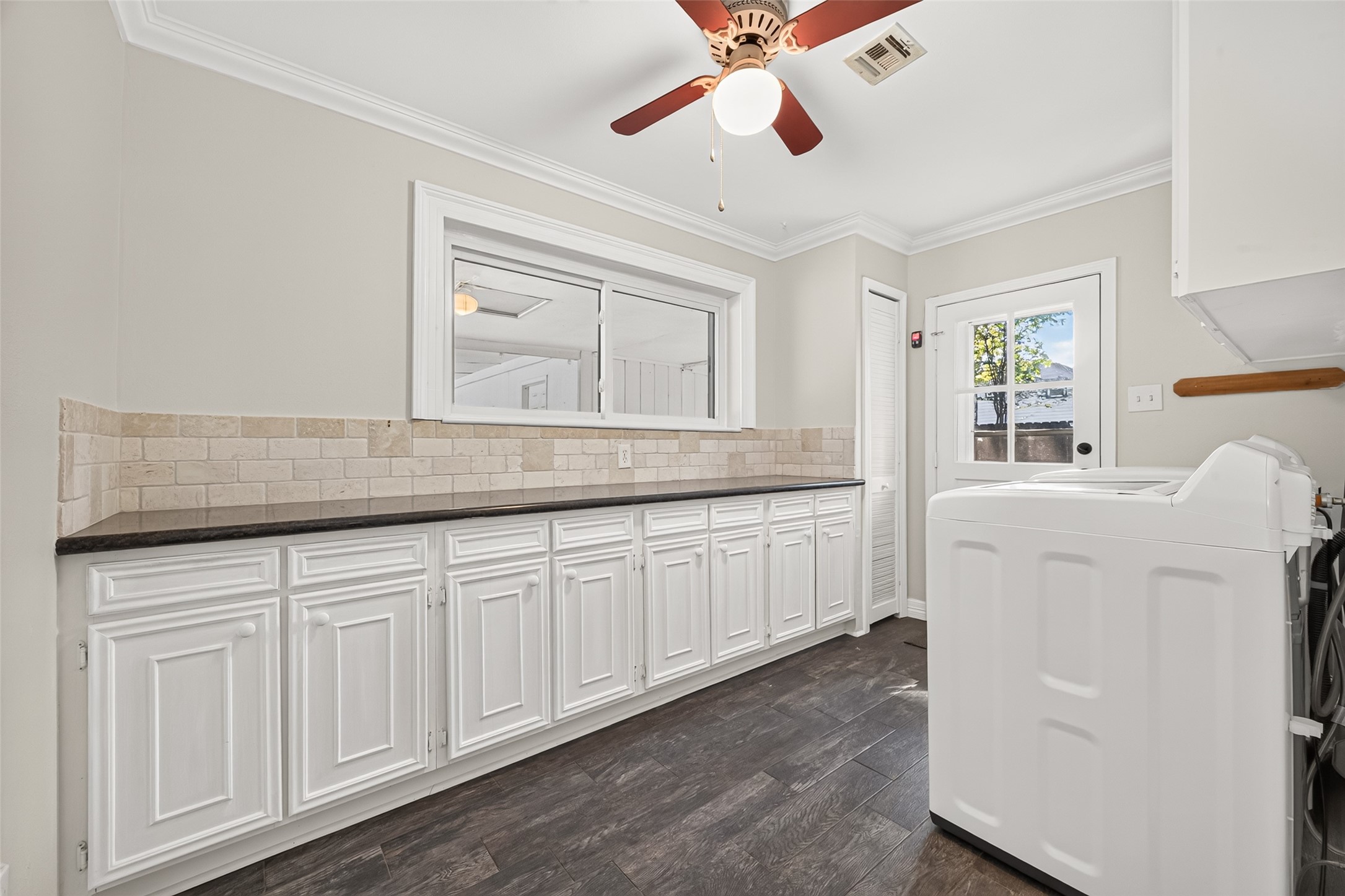 This is the utility room with an extra long granite countertop and ample cabinet storage for neatly storing mini appliances.