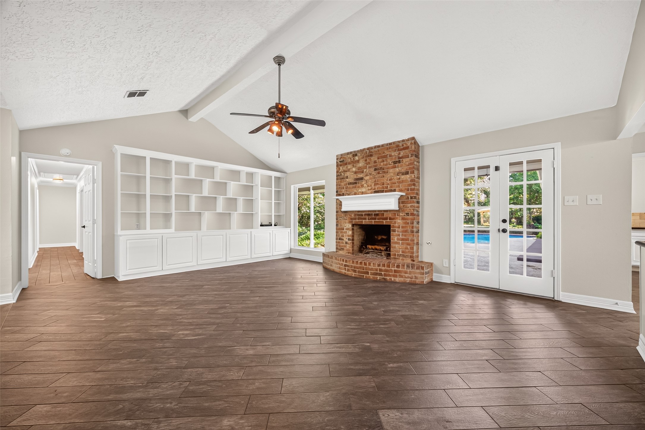 This spacious family room has so much to offer, a vaulted ceiling, deluxe built-in cabinetry and shelving, French doors opening up to the backyard oasis, and a large picture window to bathe the room in natural light.