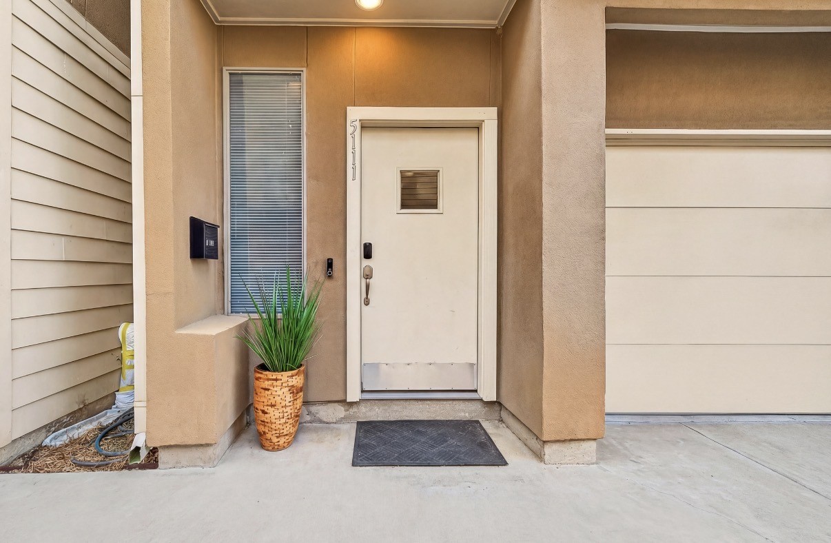 Charming entrance with a modern door and a welcoming potted plant, complemented by clean lines and contemporary design.