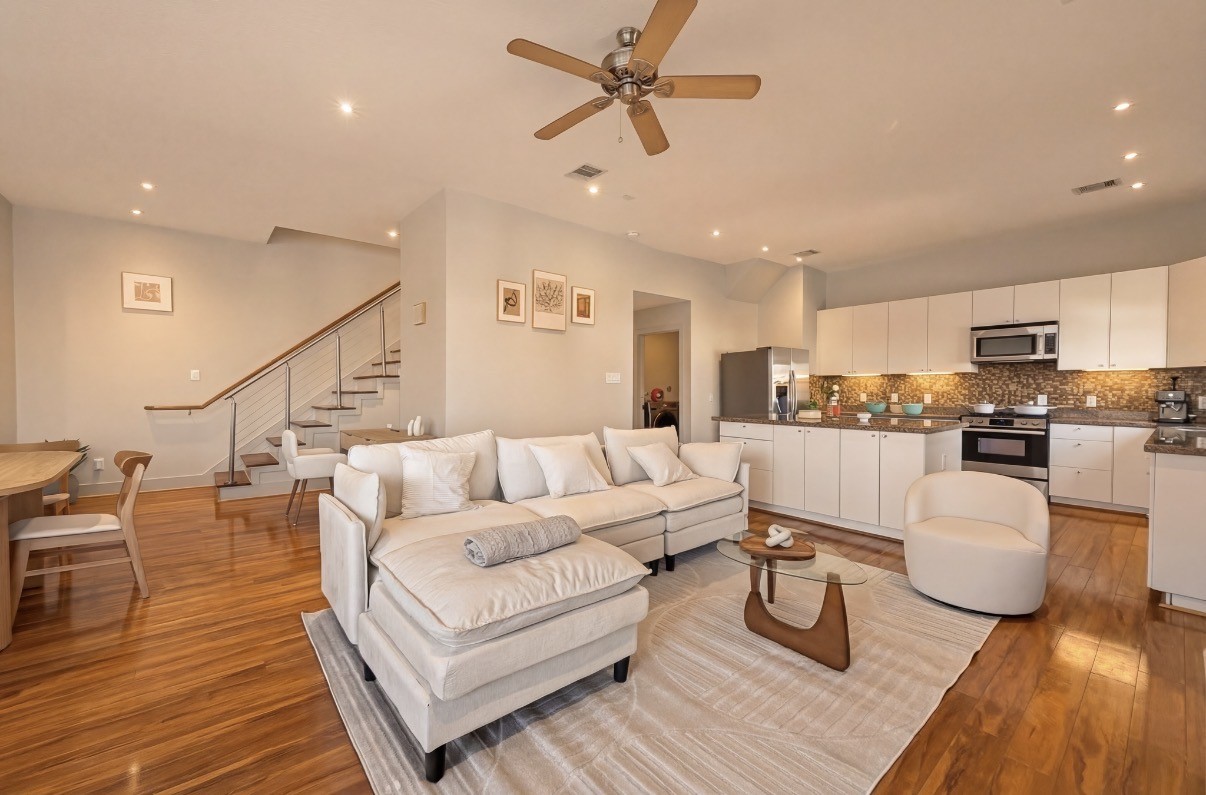 Spacious open-concept living area features sleek hardwood floors, a modern kitchen with stainless steel appliances, and a cozy seating area perfect for entertaining.