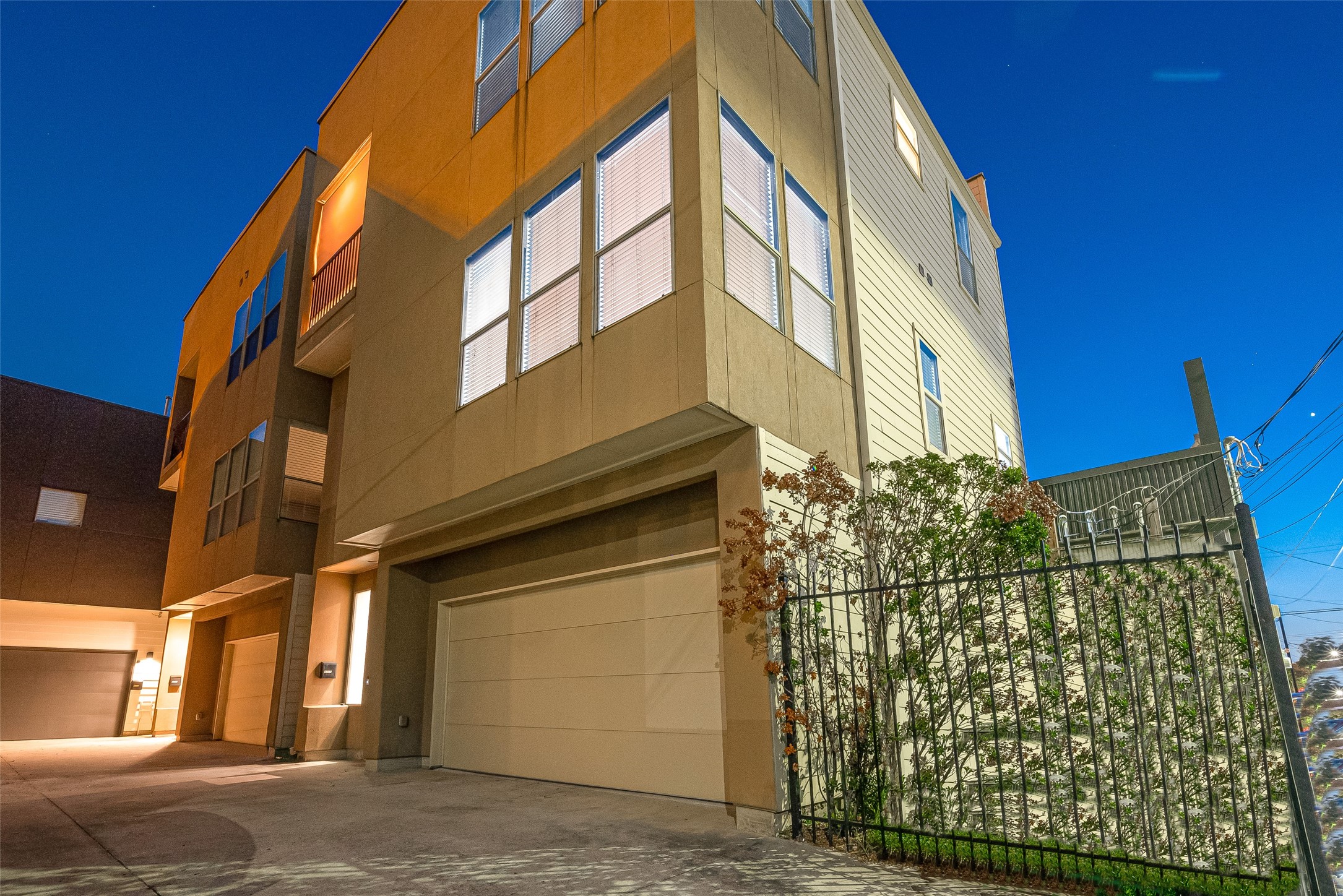 Modern multi-story home with large windows and an attached garage, set in a well-lit urban neighborhood.
