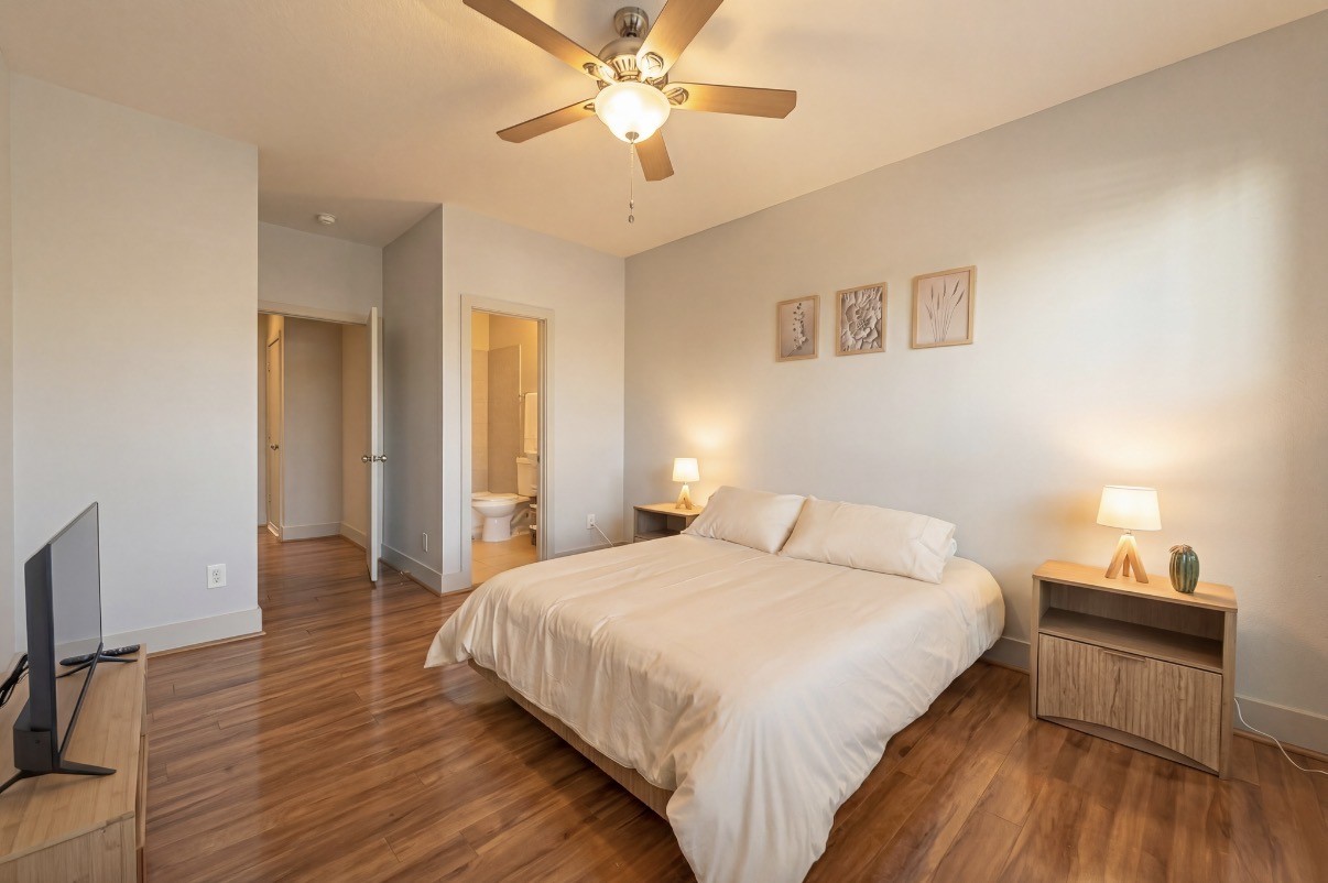 Spacious third bedroom on THIRD floor with warm wood flooring, a cozy bed, and soft lighting from bedside lamps, offering a serene and inviting atmosphere.