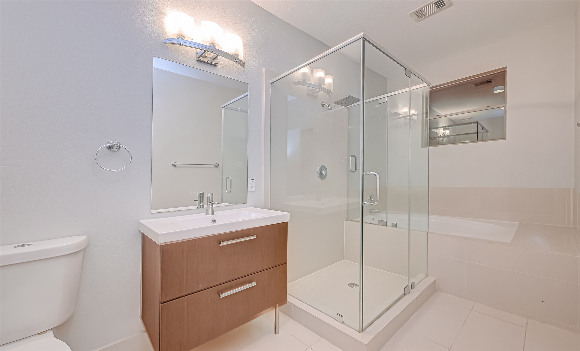 Modern bathroom featuring a sleek glass-enclosed shower, elegant vanity with ample storage, and a relaxing soaking tub.