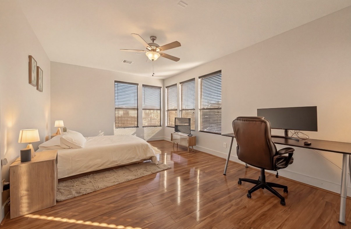 Spacious Master bedroom on THIRD floor with abundant natural light, featuring sleek hardwood floors, a cozy bed, and a convenient workstation.