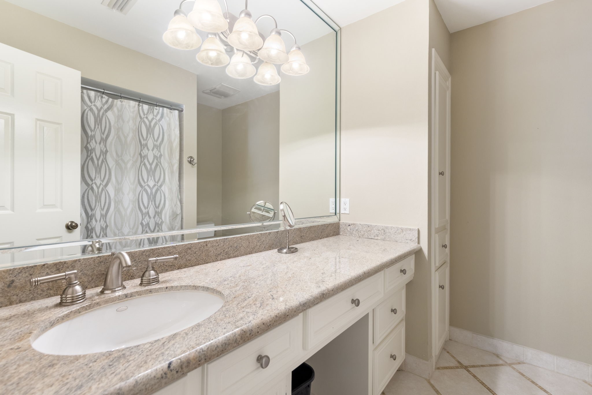 An extended bathroom counter and abundant cabinetry provide useful storage and space for daily essentials.