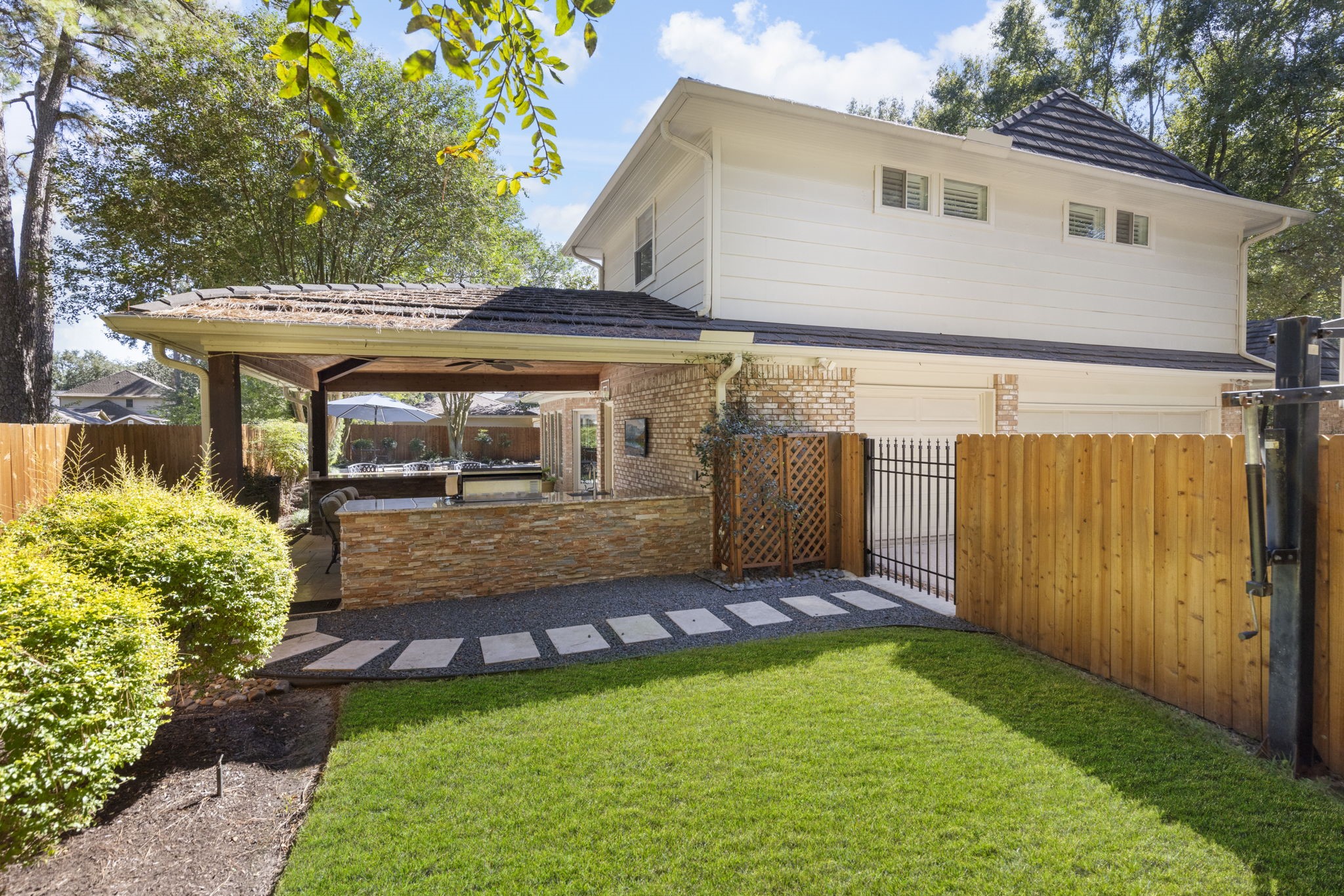 A manageable stretch of lawn and stepping stone path complement the stained cedar fence installed in 2025.
