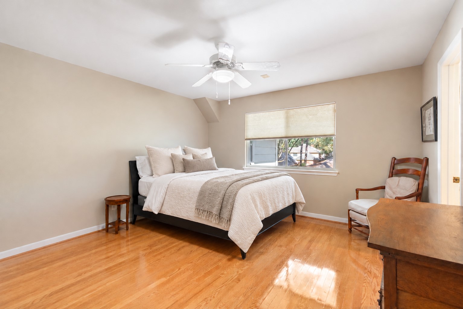Wood flooring and a wide window give this secondary oversized bedroom a bright, welcoming feel with flexibility for guests or everyday living.