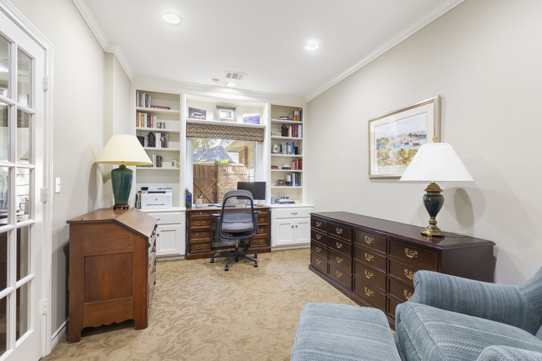 Built in shelving and a window overlooking greenery make this adjoining room an appealing place for a home office or personal library.