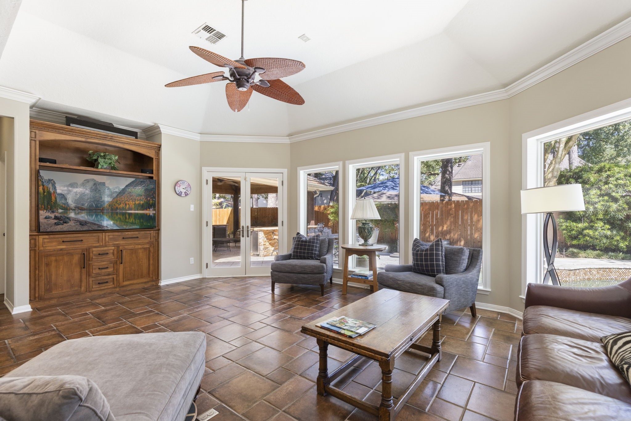 Sunlight pours through a wall of windows in this inviting sunroom, where pool views become part of everyday living.