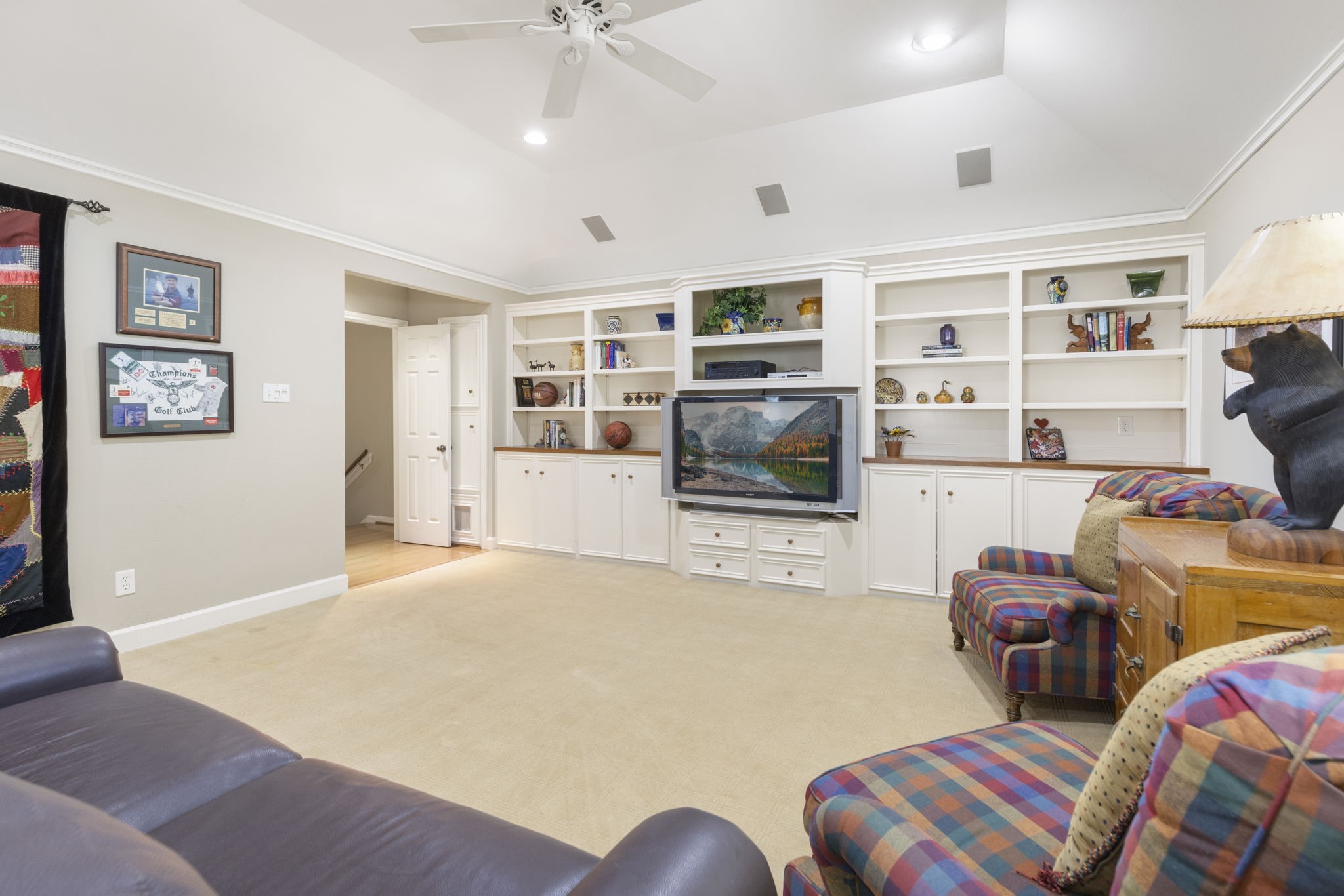 Custom built ins combine display shelving, enclosed storage, and a central media niche to keep the game room organized.