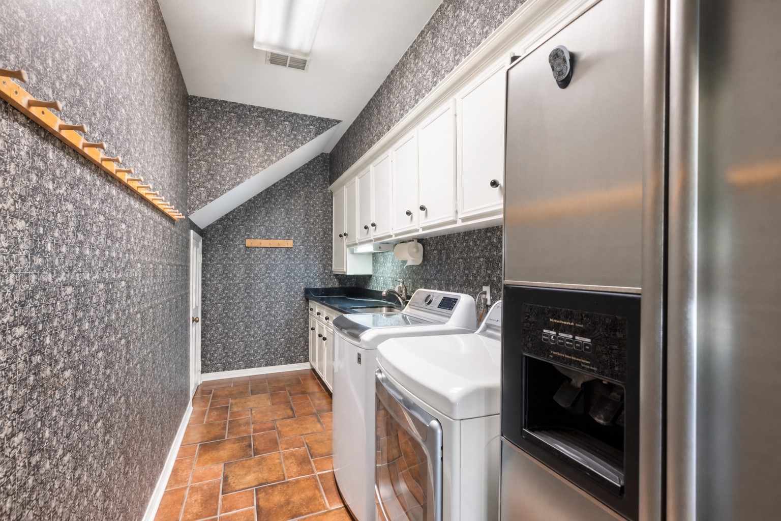 Upper cabinets, a utility sink, and a hanging rod bring everyday convenience to the dedicated laundry room.