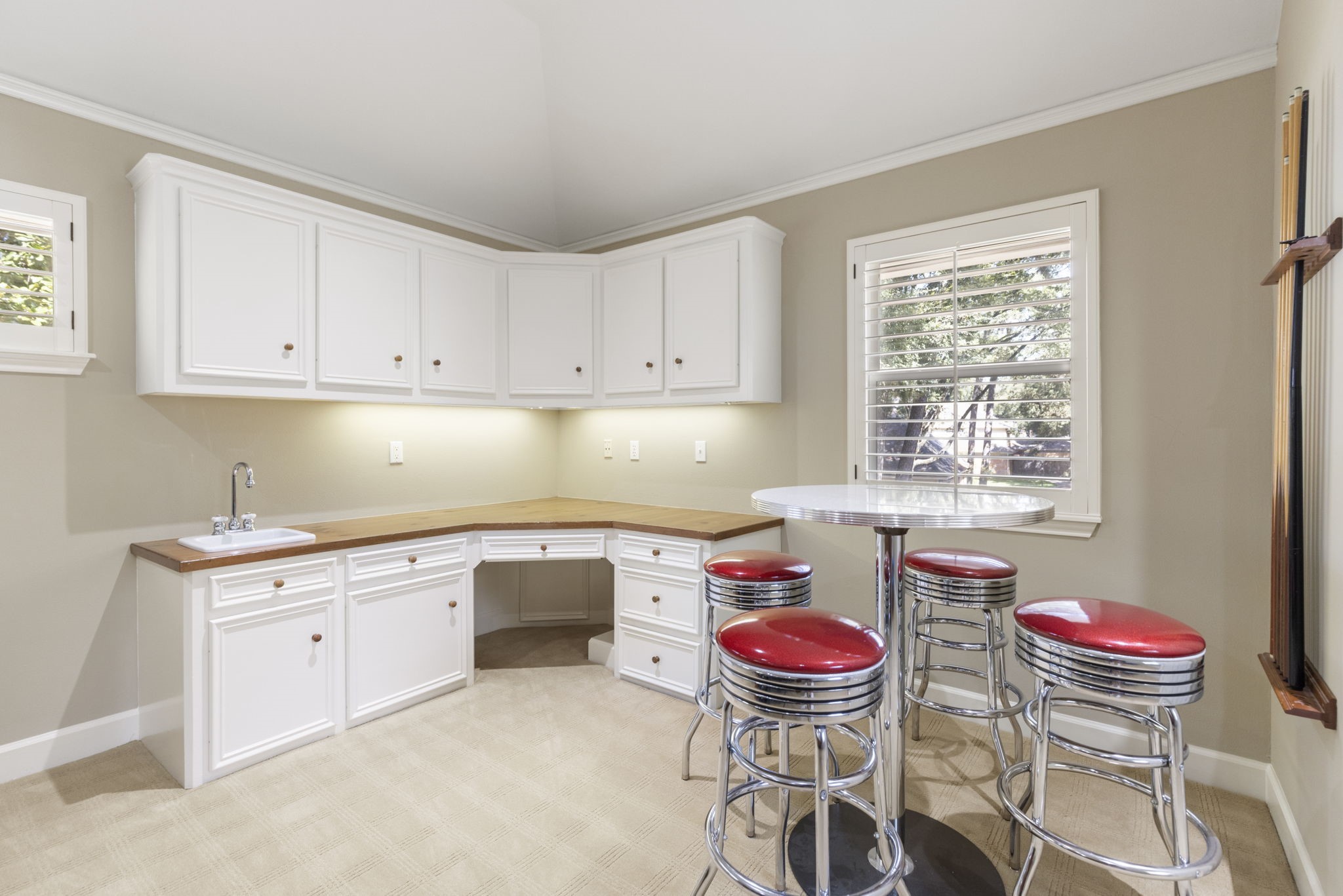 A convenient kitchenette with a sink, cabinetry, and counter seating keeps snacks and refreshments close to the game room.