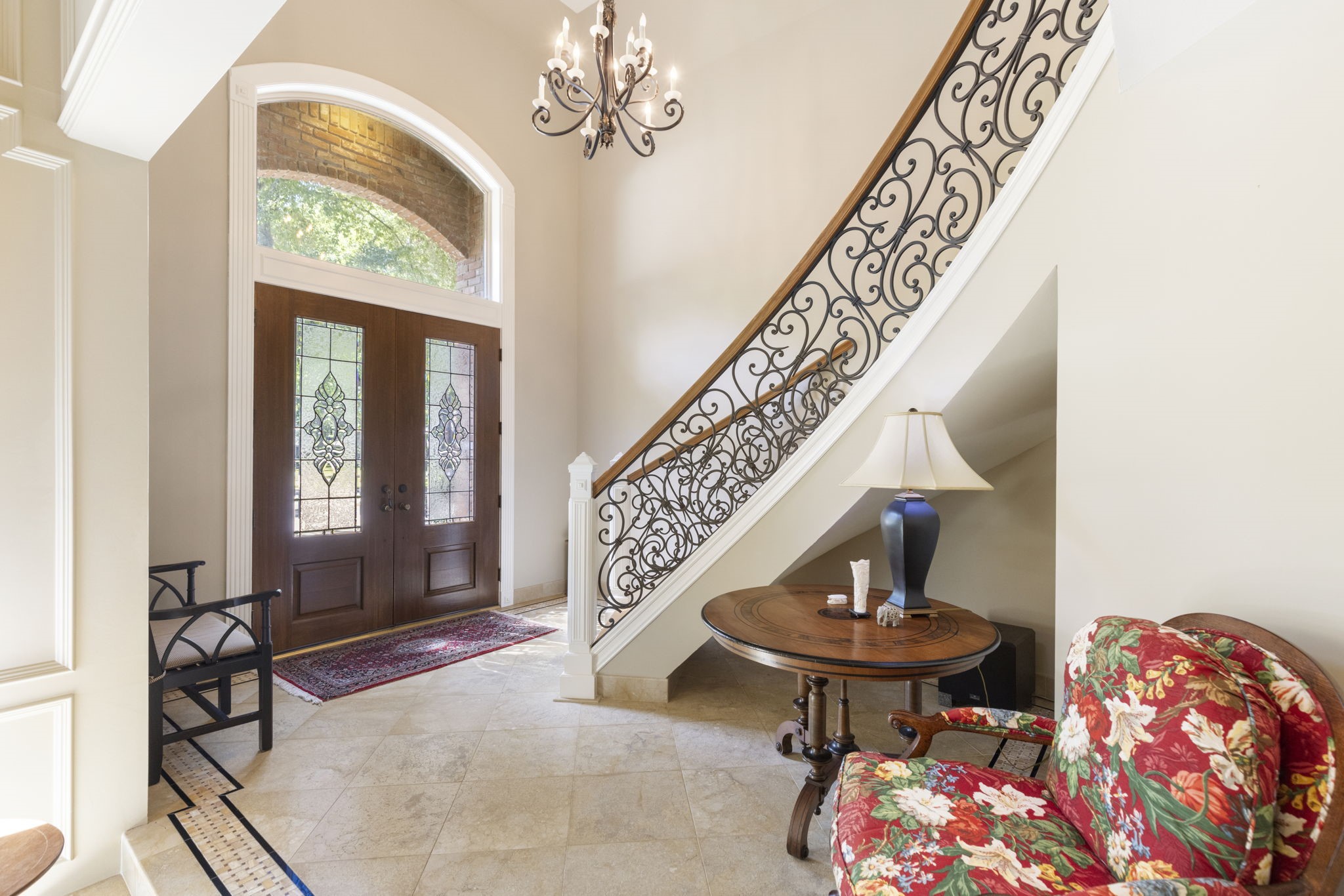 Curved stair detailing and richly framed entry doors bring architectural character to a welcoming foyer with inviting views into the living spaces.